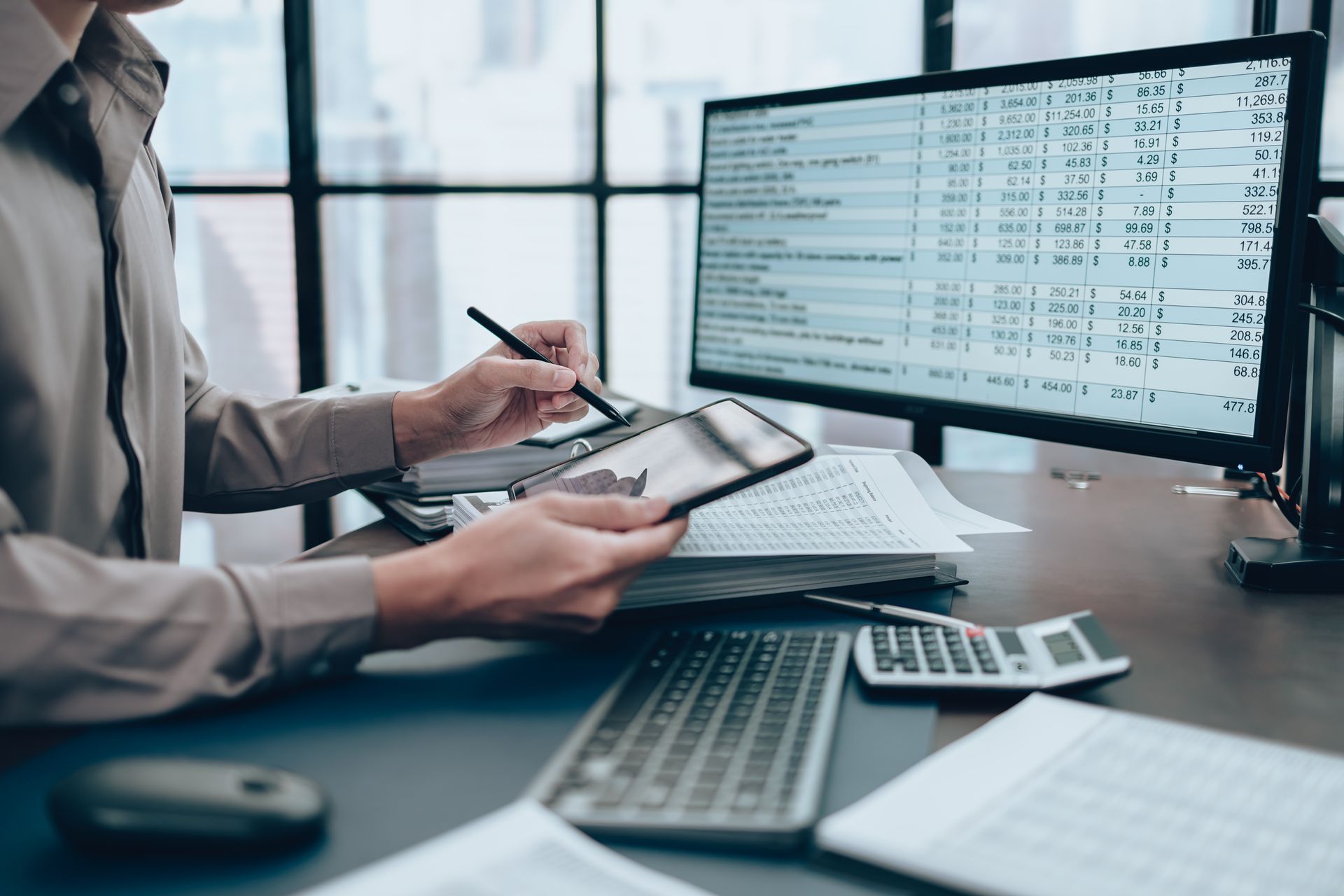 A man is sitting at a desk using a tablet and a computer.
