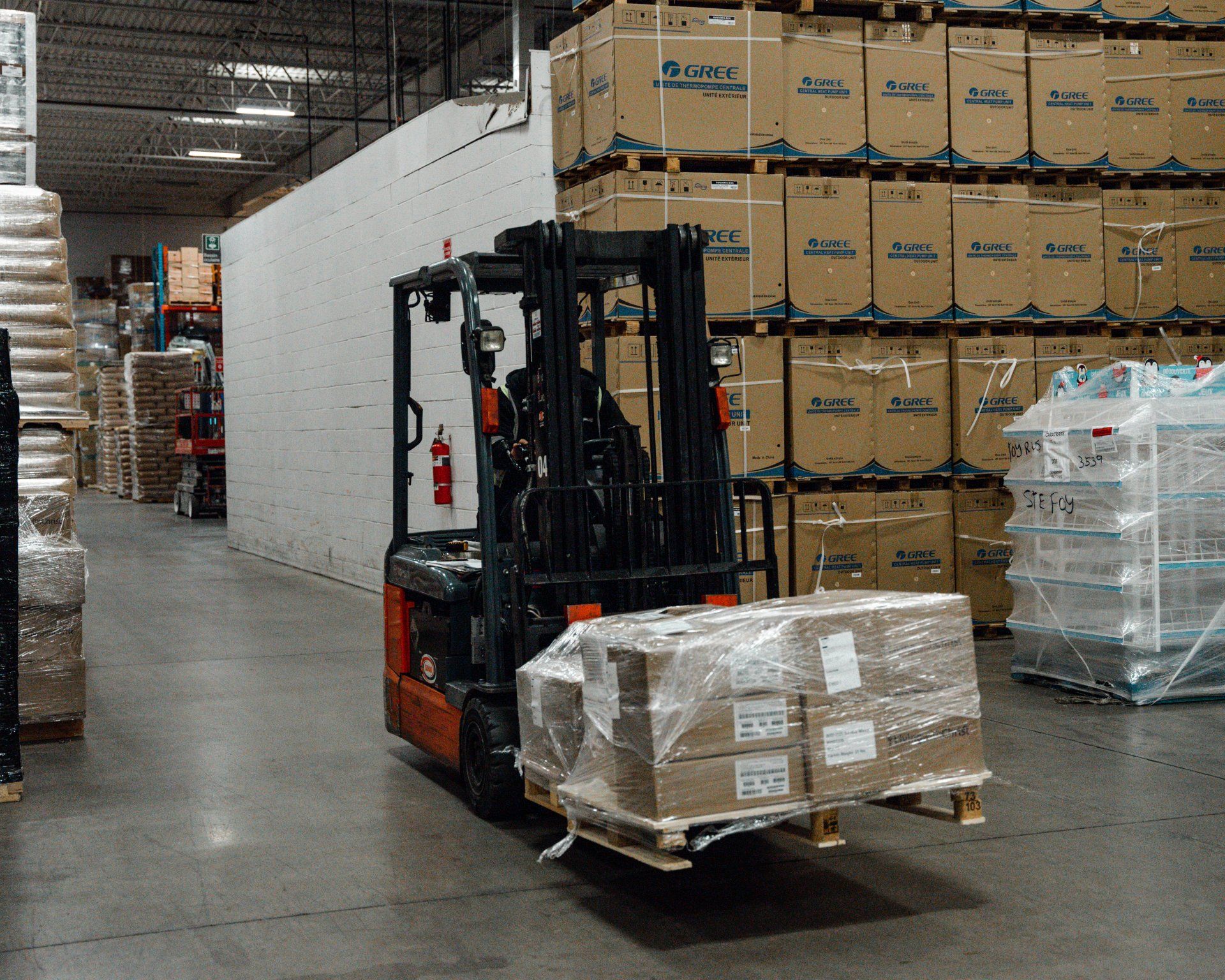 Un chariot élévateur transporte des cartons dans un grand entrepôt