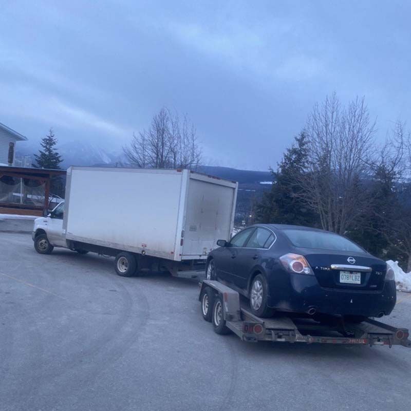 A car is being towed by a white truck.