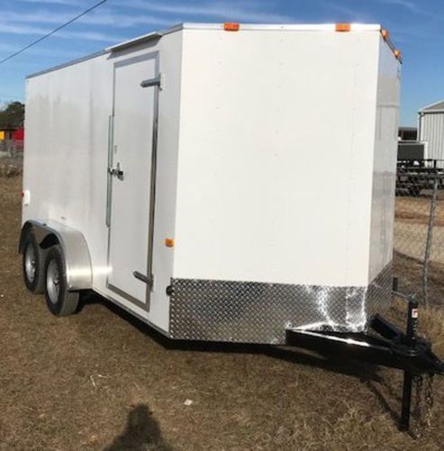 A white trailer is parked in a field next to a fence.