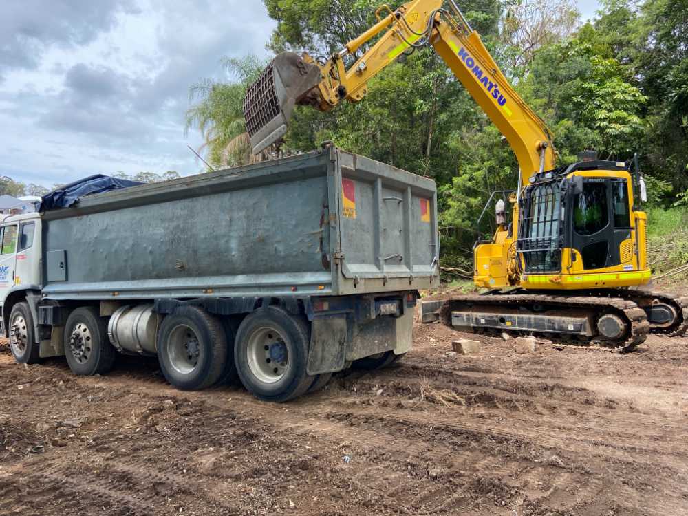 Komatsu Digger loading dirt into the bed if a truck — Allcoast Group Demolition Contractors from Gallery in Sunshine Coast, QLD