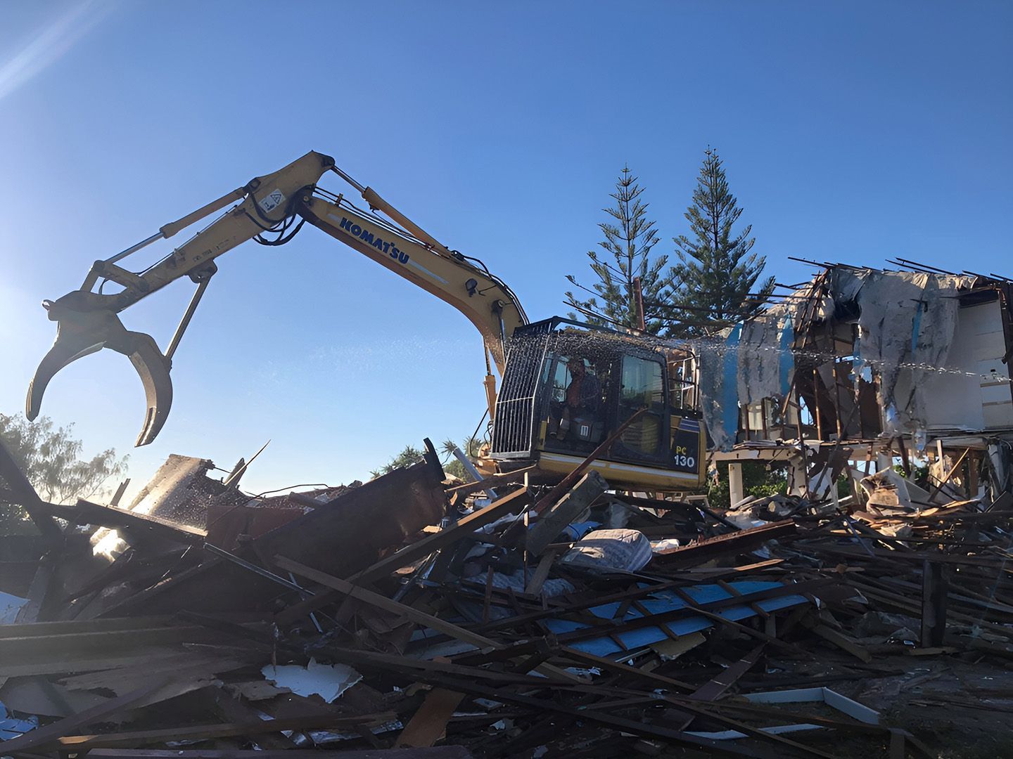 Excavator Demolishing House Structure Amid Debris At Worksite