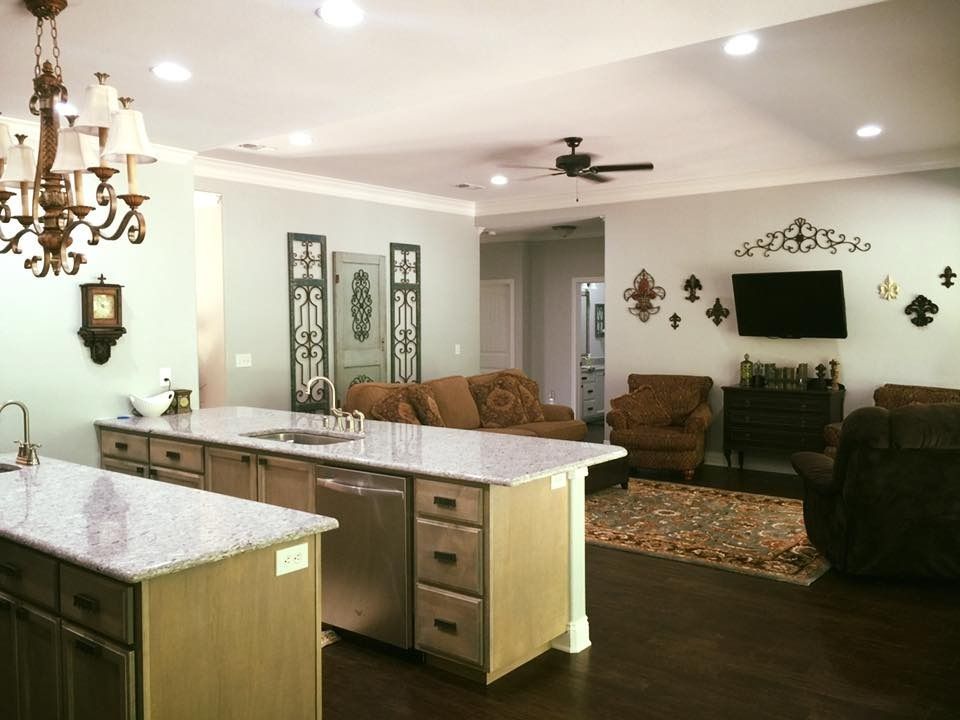Open-concept living space with kitchen island, seating area, dark wood floors, and decorative wall art.