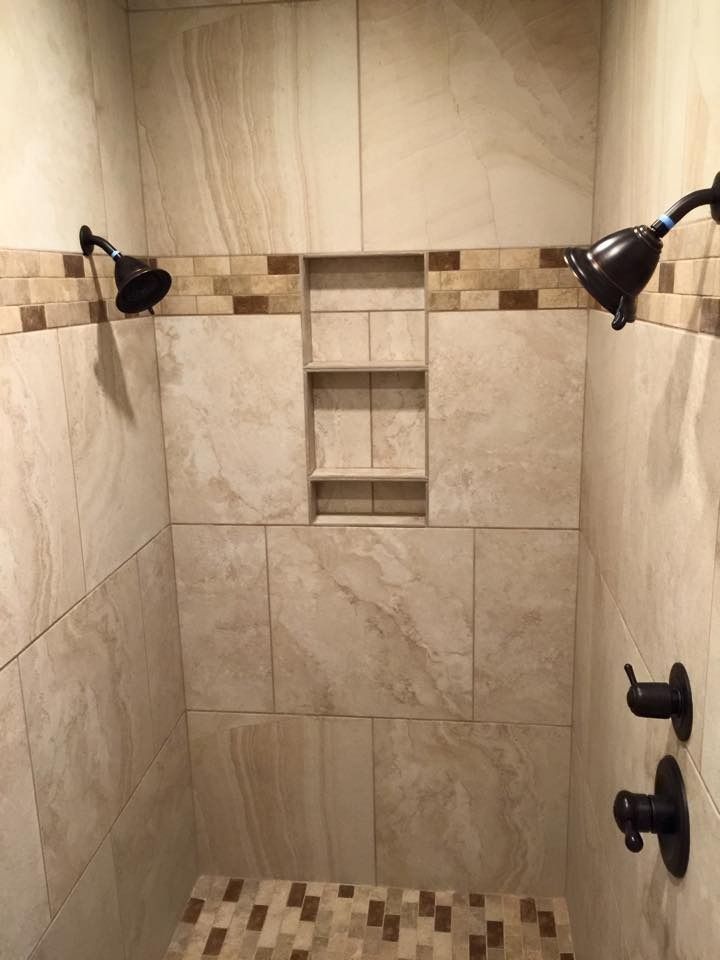 Tiled shower with two showerheads, a recessed shelf, and bronze fixtures.