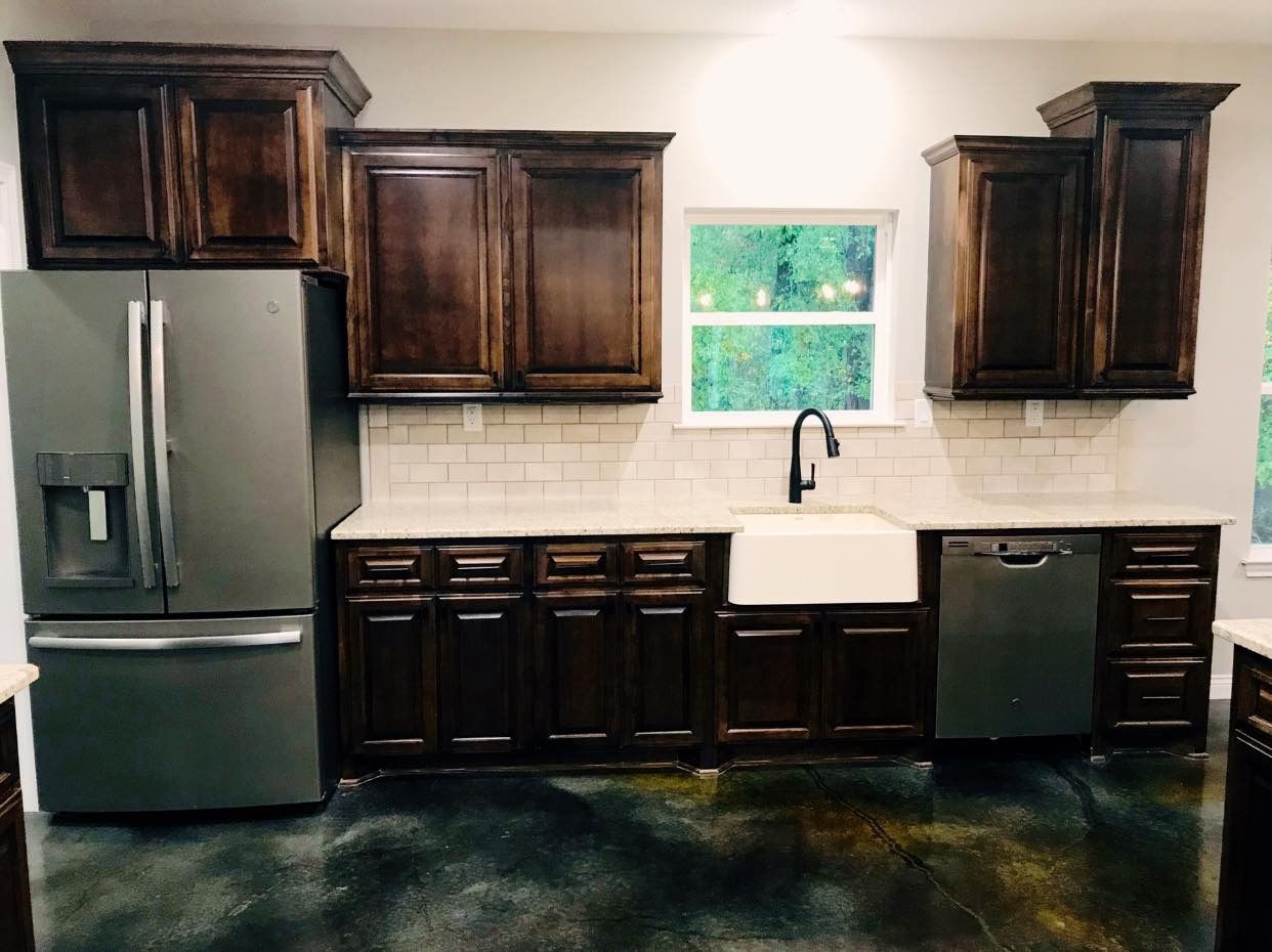 Kitchen with dark wood cabinets, stainless steel appliances, white countertops, and a farm sink.