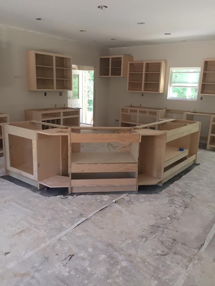 Unfinished kitchen with installed light-colored cabinetry; a central island is in focus.