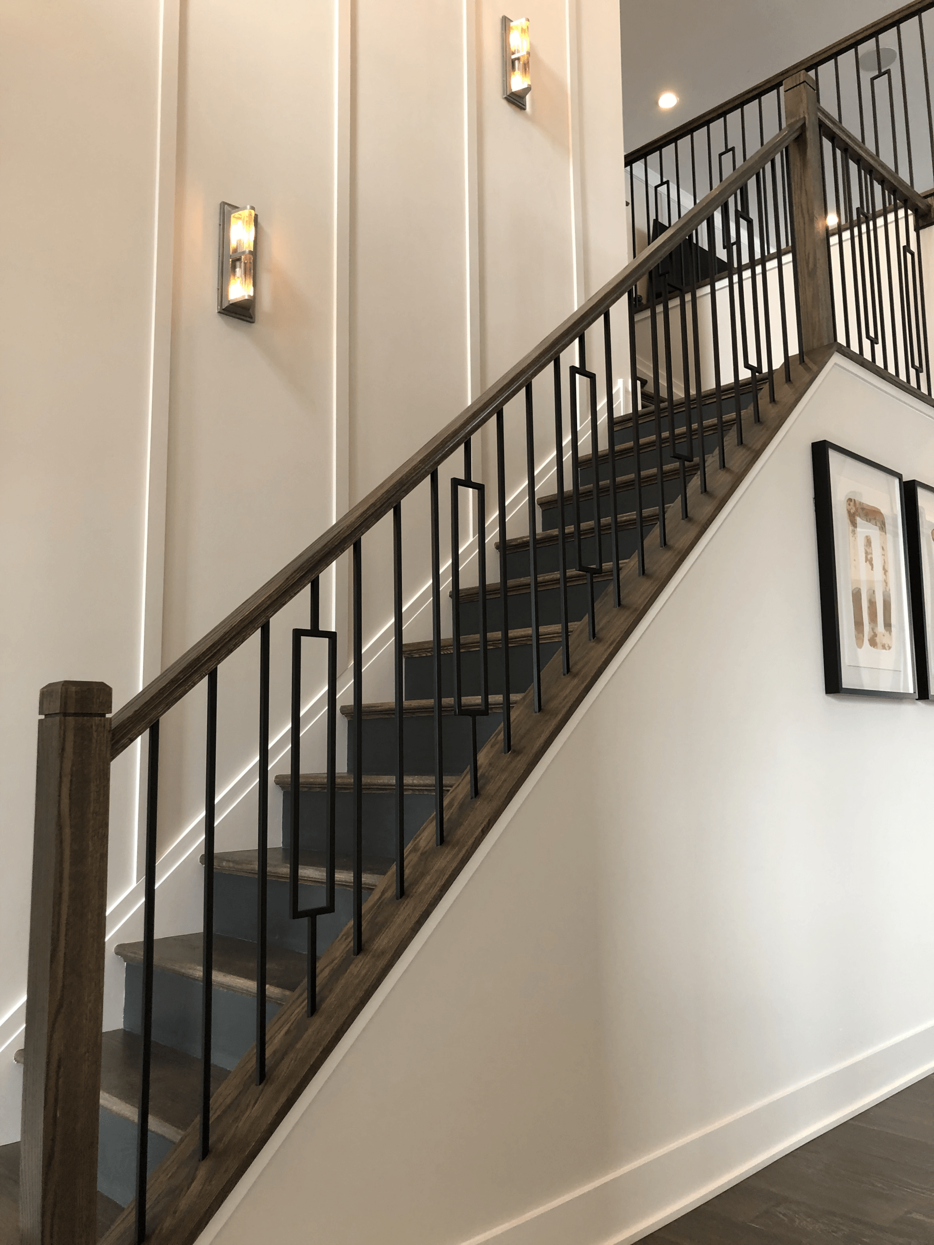 A wooden staircase with a metal railing in a hallway.