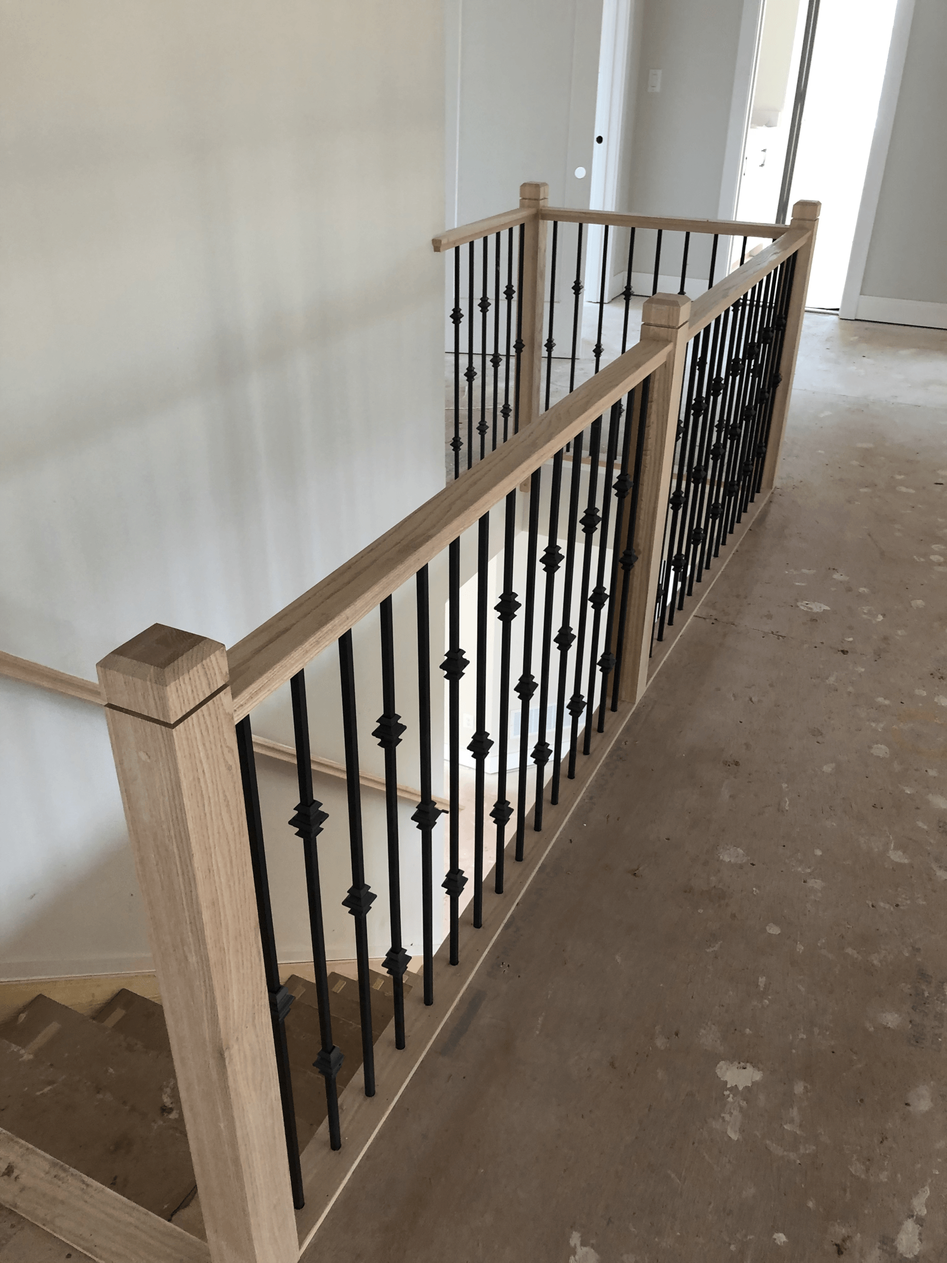 A wooden staircase with a wrought iron railing in a room.