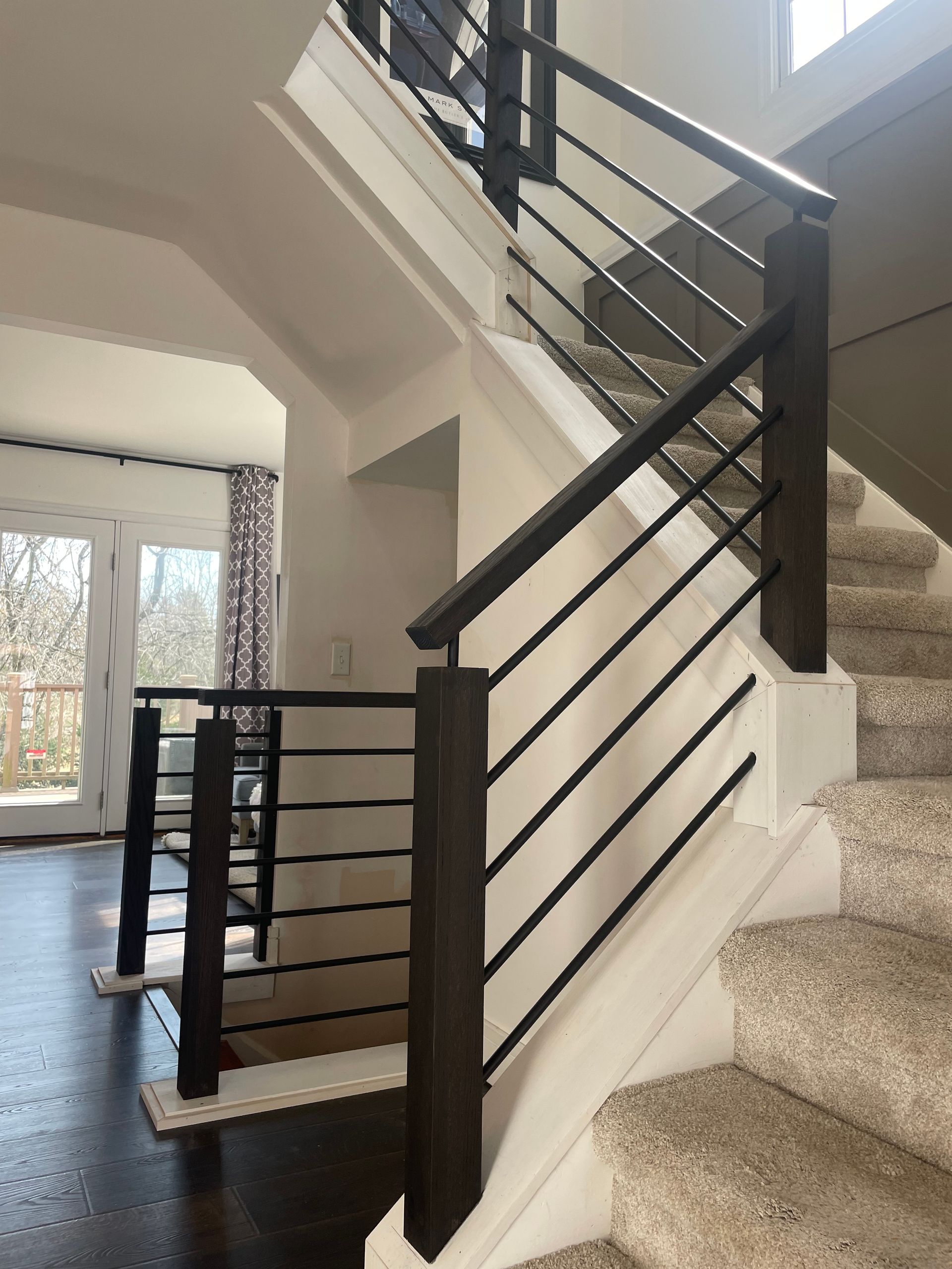 A staircase with a black railing and carpeted steps