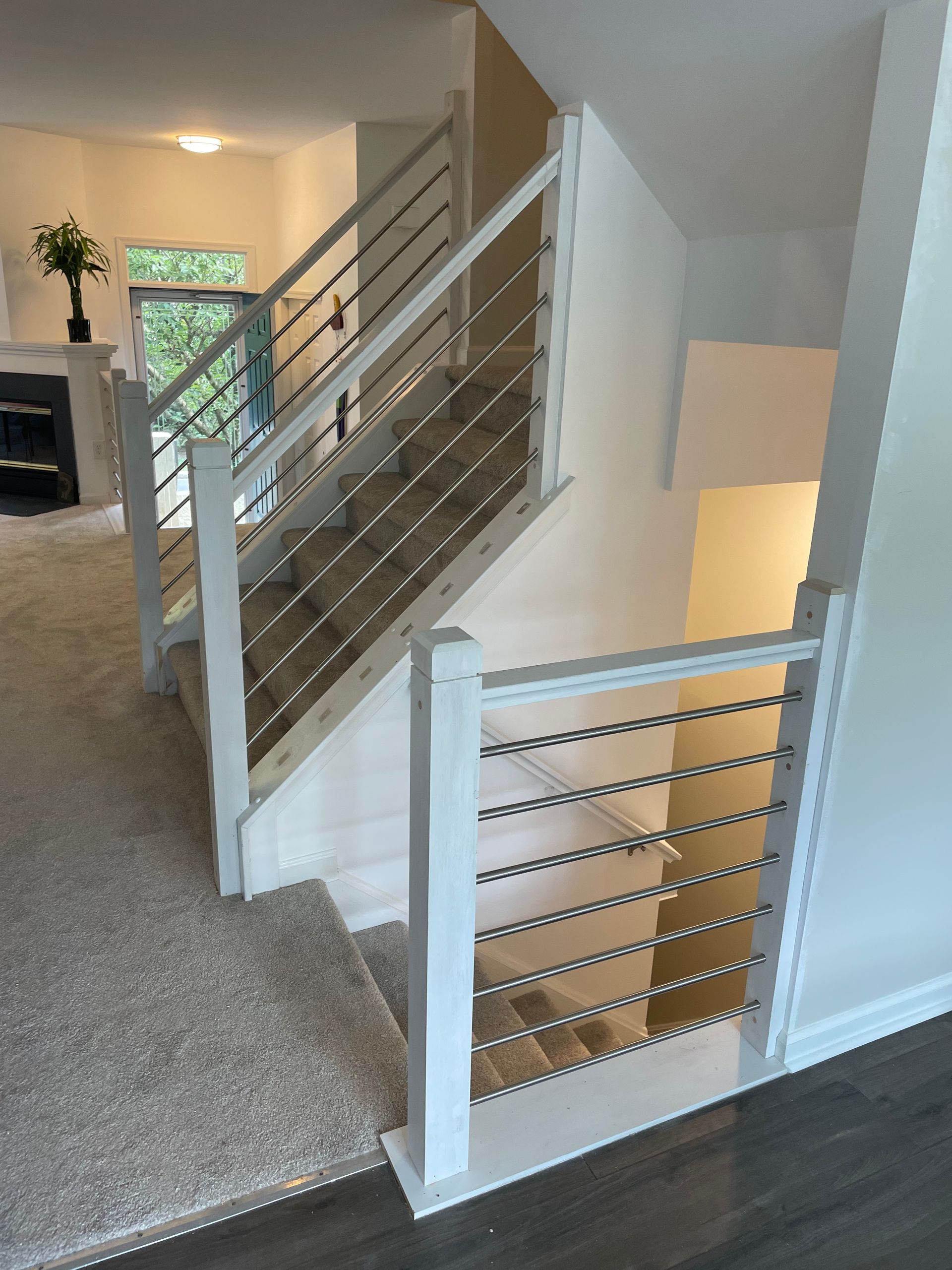 A white staircase with a stainless steel railing in a house