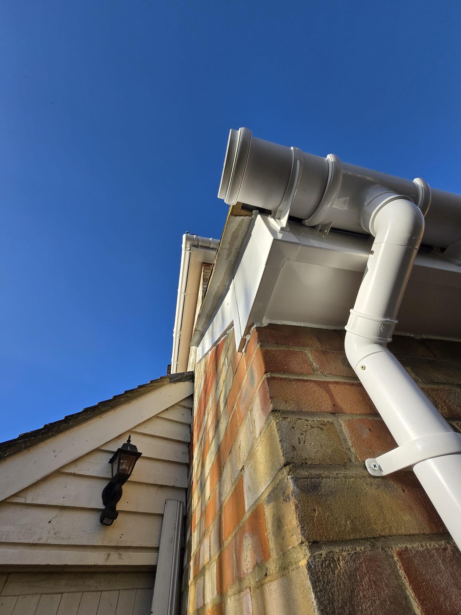 White gutters on a brick building with a blue sky background.