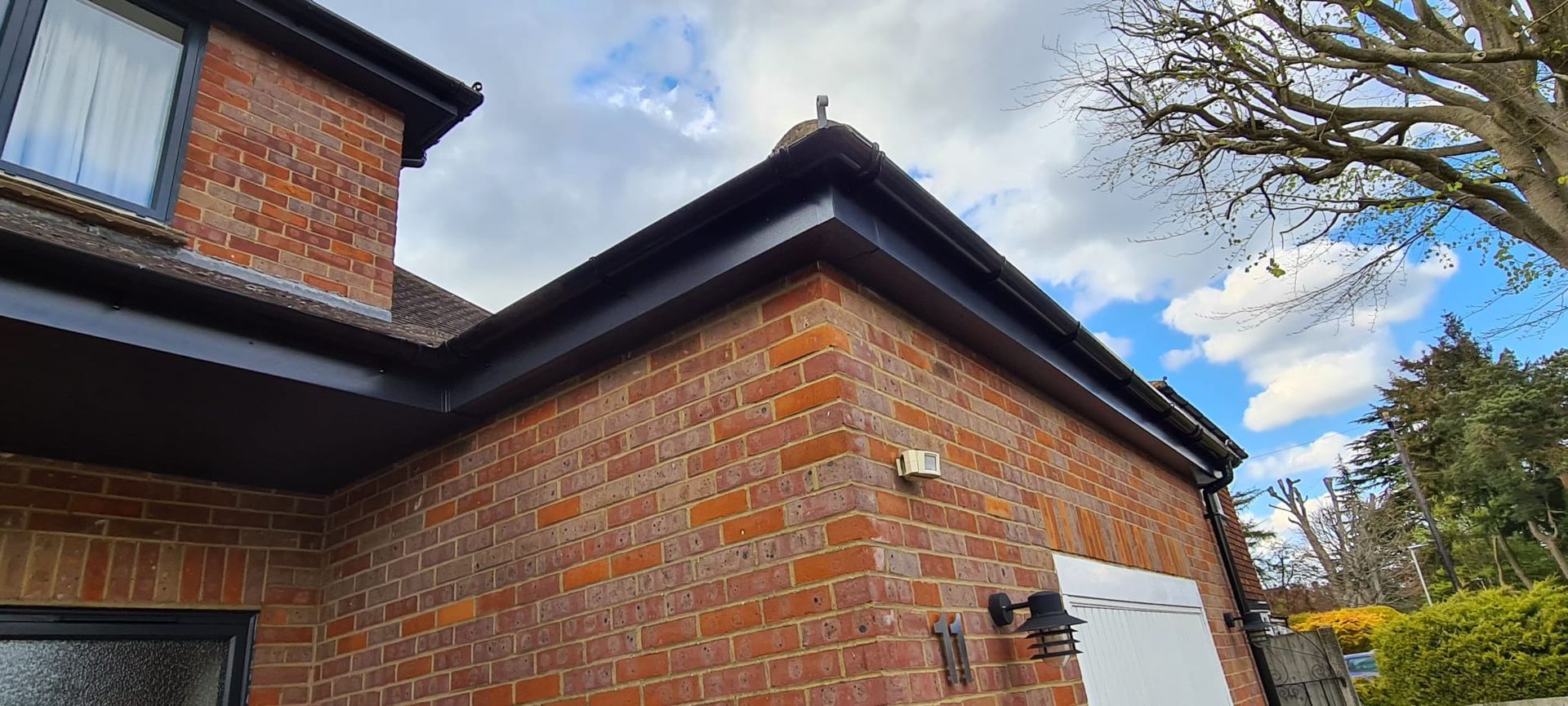 Brick building exterior with dark trim and a cloudy sky in the background.