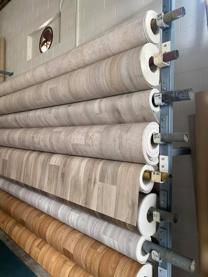 Rolls Of Patterned Flooring Stacked On A Metal Rack In A Warehouse Setting — Mareeba Floor Covering Centre in Mareeba, QLD