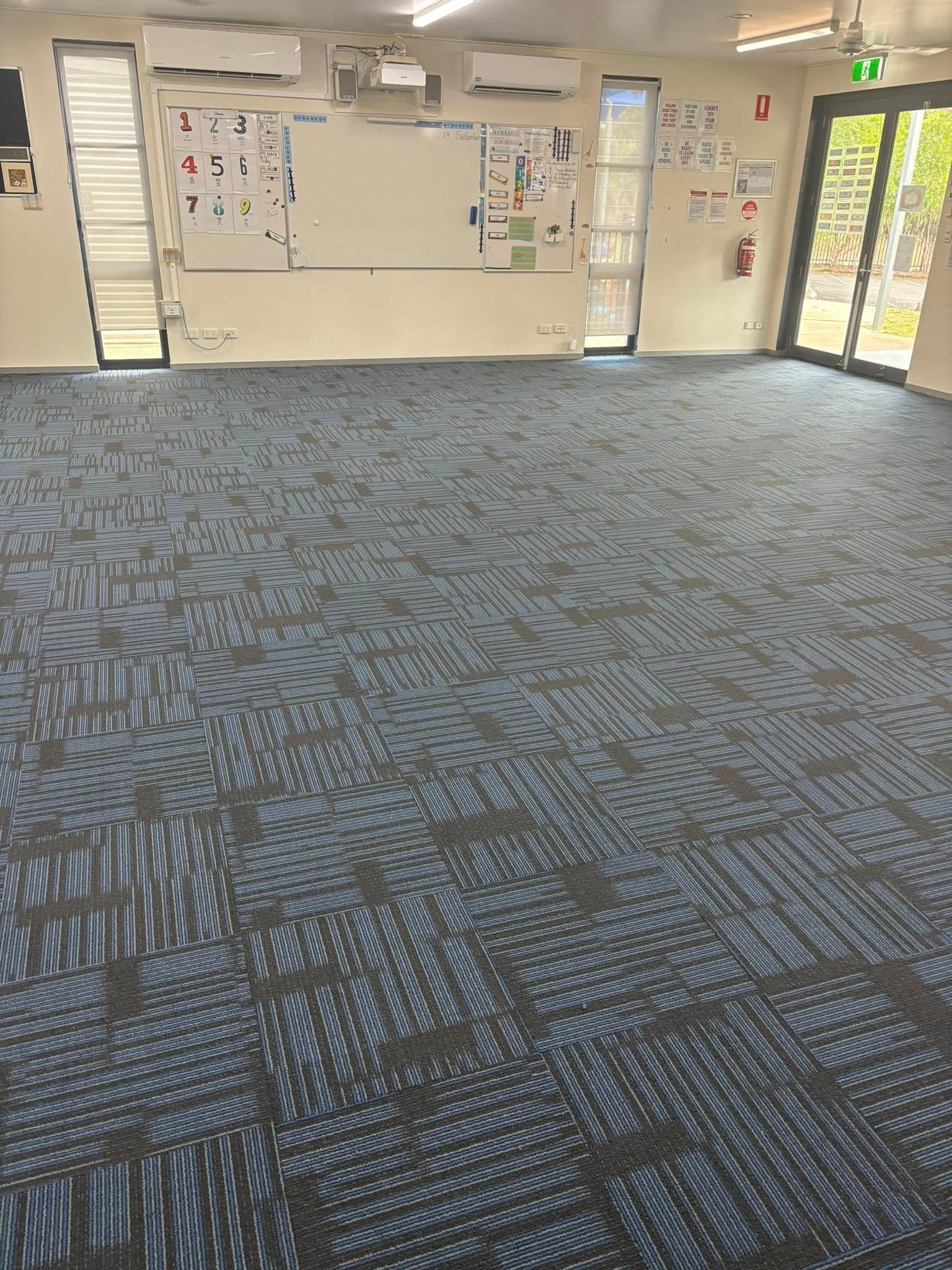 Empty room with blue patterned carpet, white walls, and a whiteboard — Mareeba Floor Covering Centre in Cassowary Coast, QLD