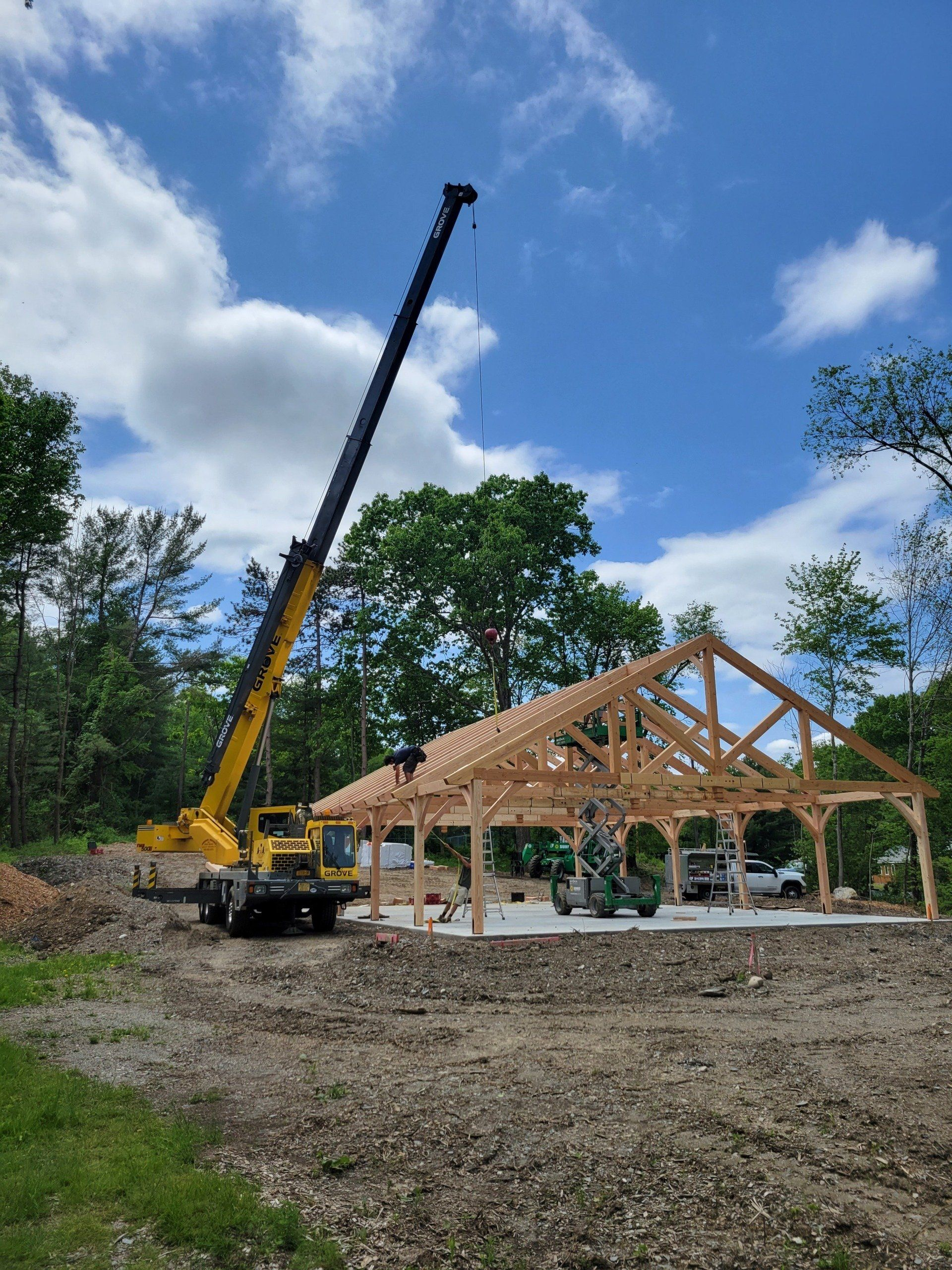 A crane is lifting a wooden structure in a field.