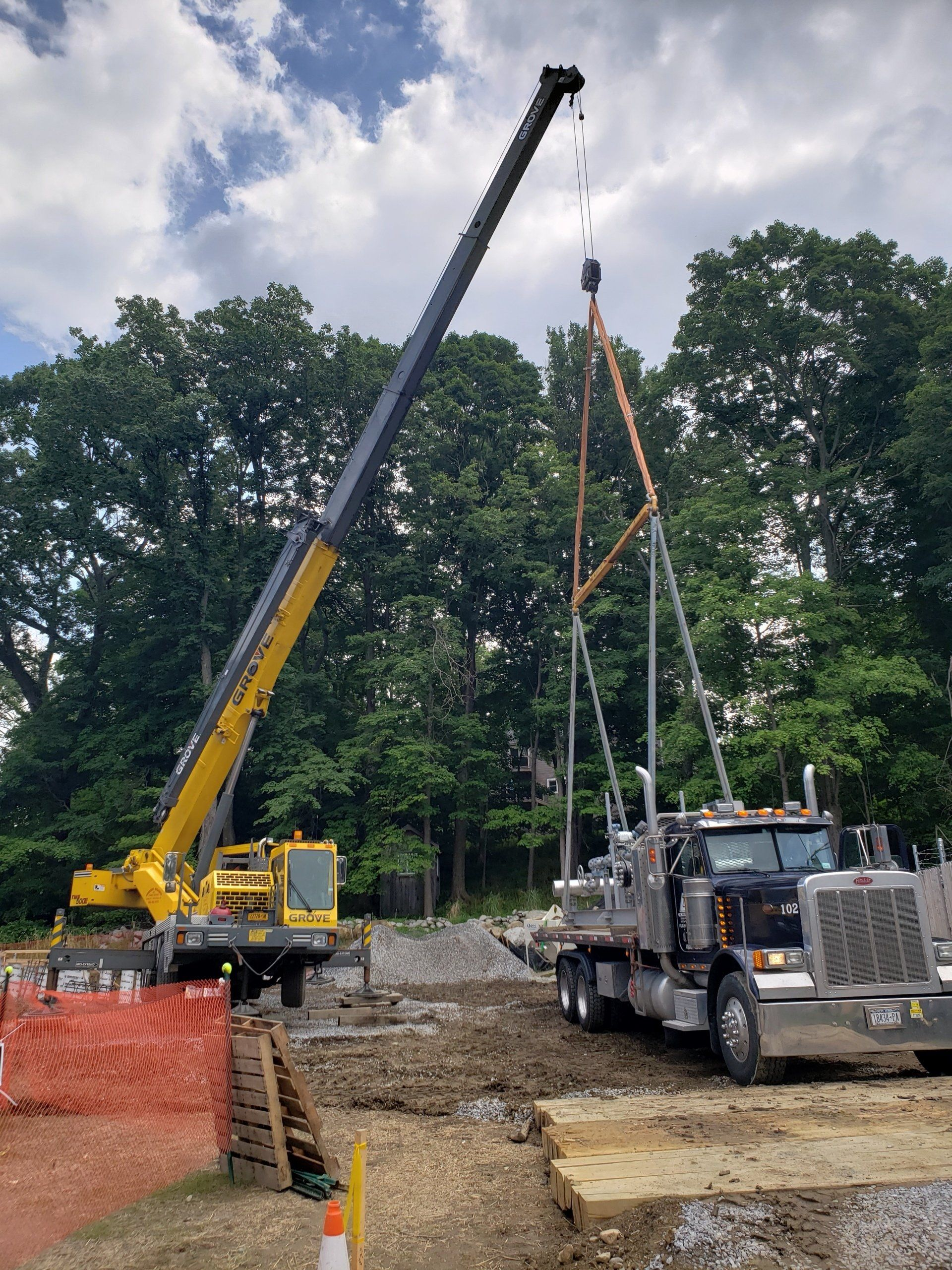 A crane is lifting a large piece of metal on top of a truck.