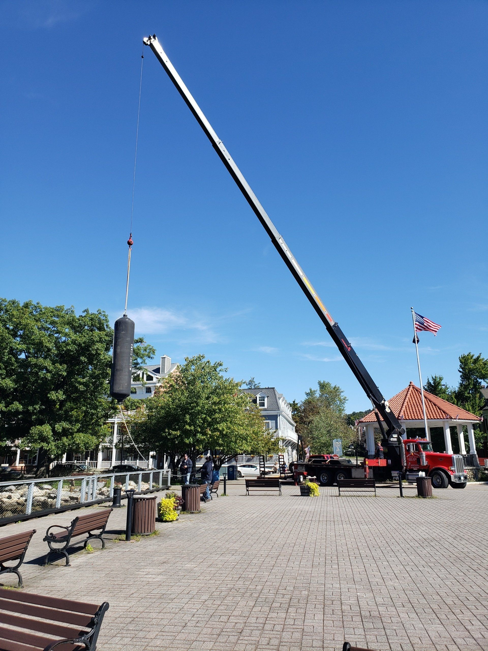 A large crane is lifting a large object in a park