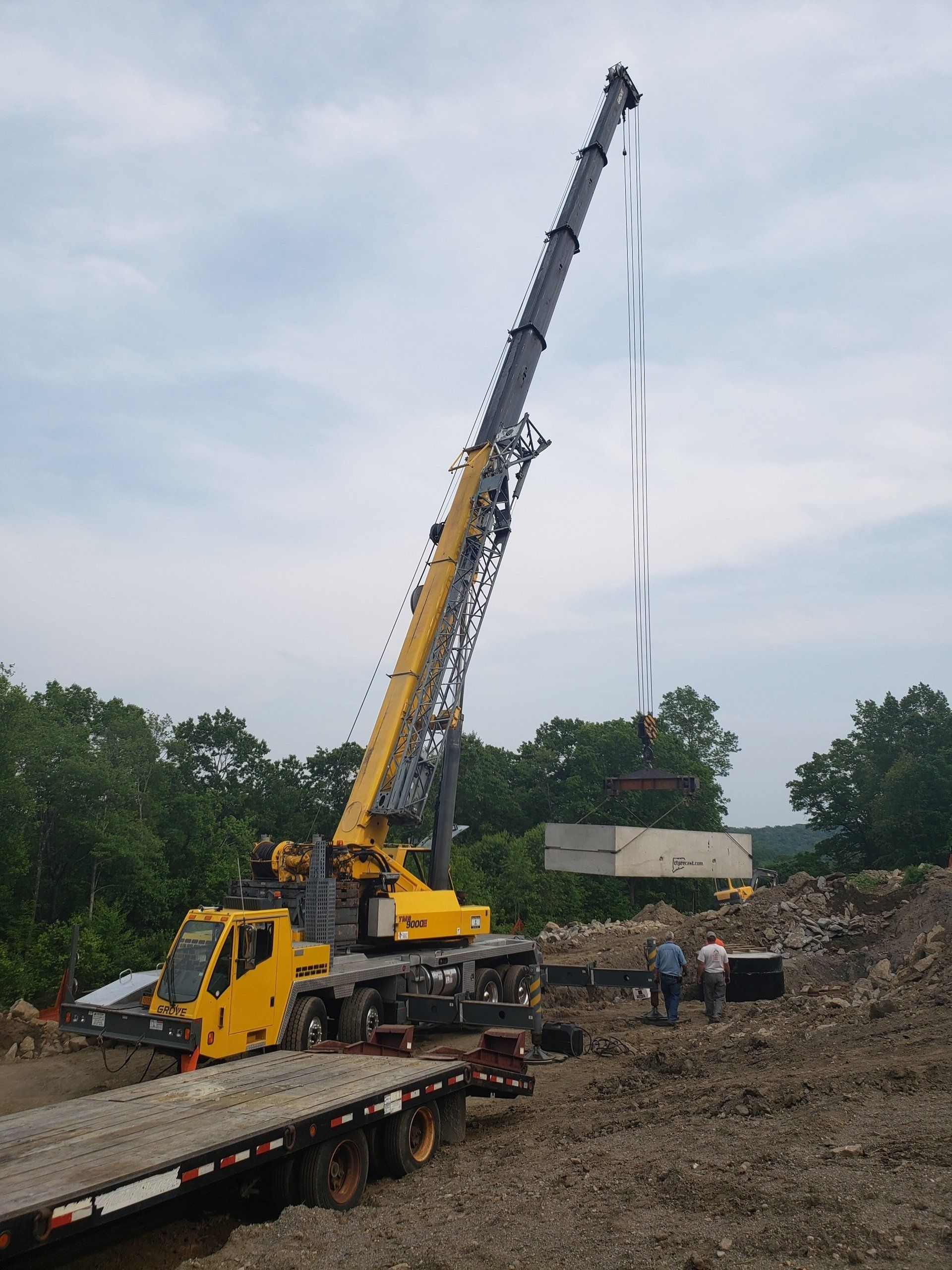 A large yellow crane is sitting on top of a flatbed truck.