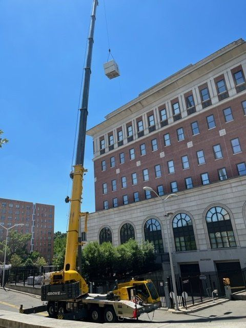 A crane is lifting a box in front of a large building