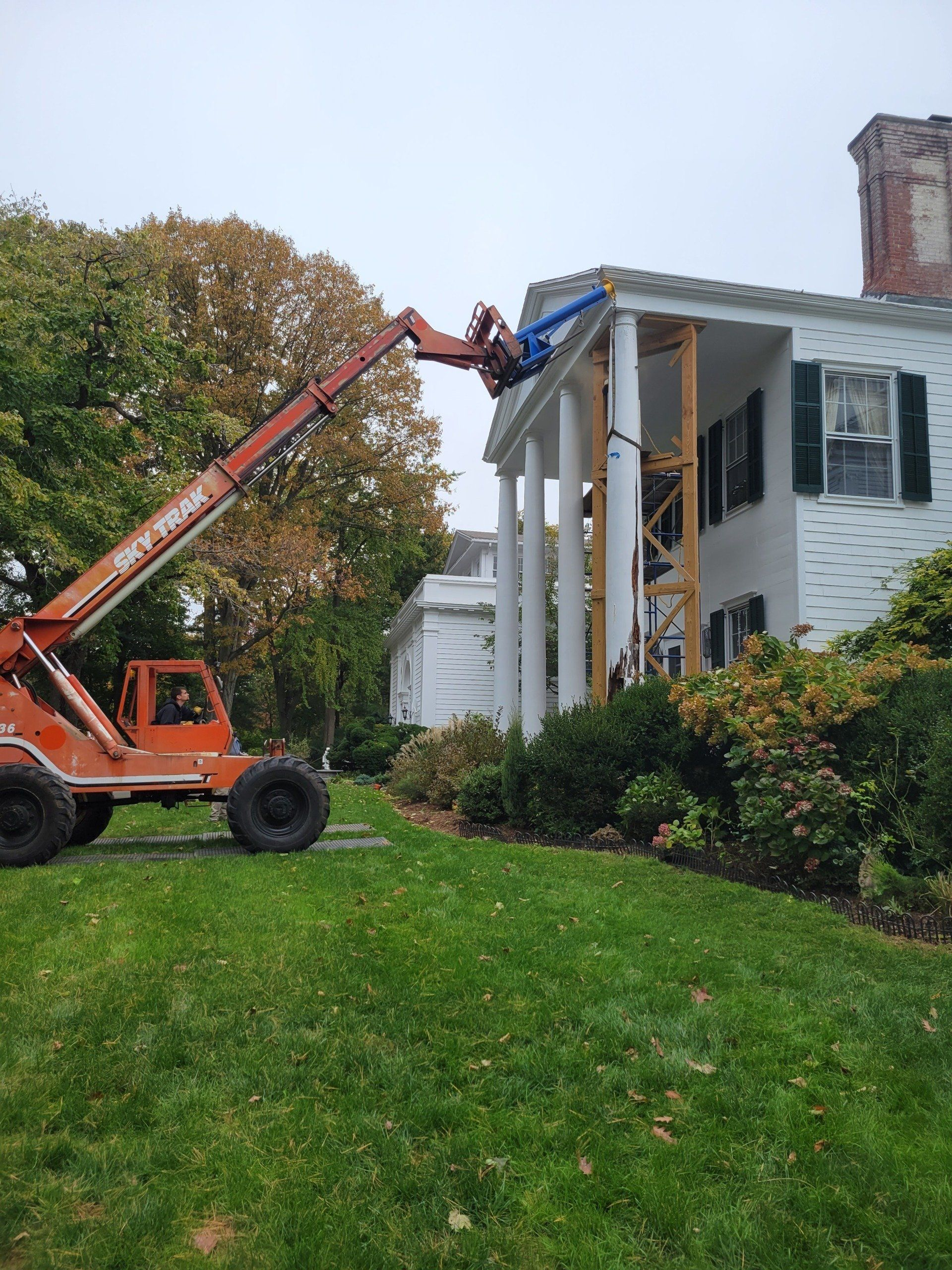 A man is working on the roof of a house with a forklift.