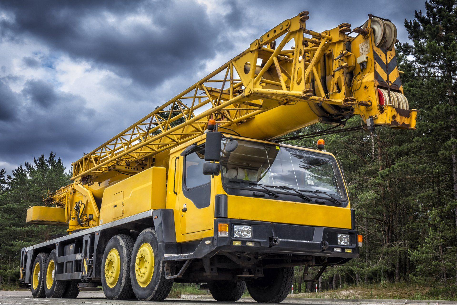 A yellow crane truck is parked on the side of the road.