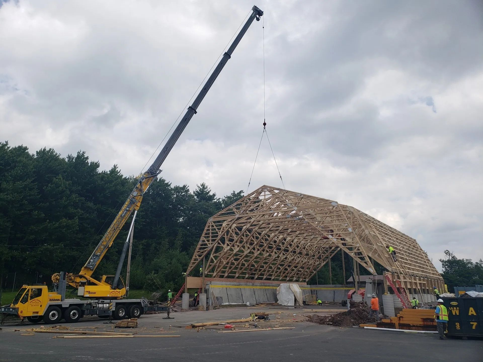 A large yellow crane is lifting a large wooden structure.