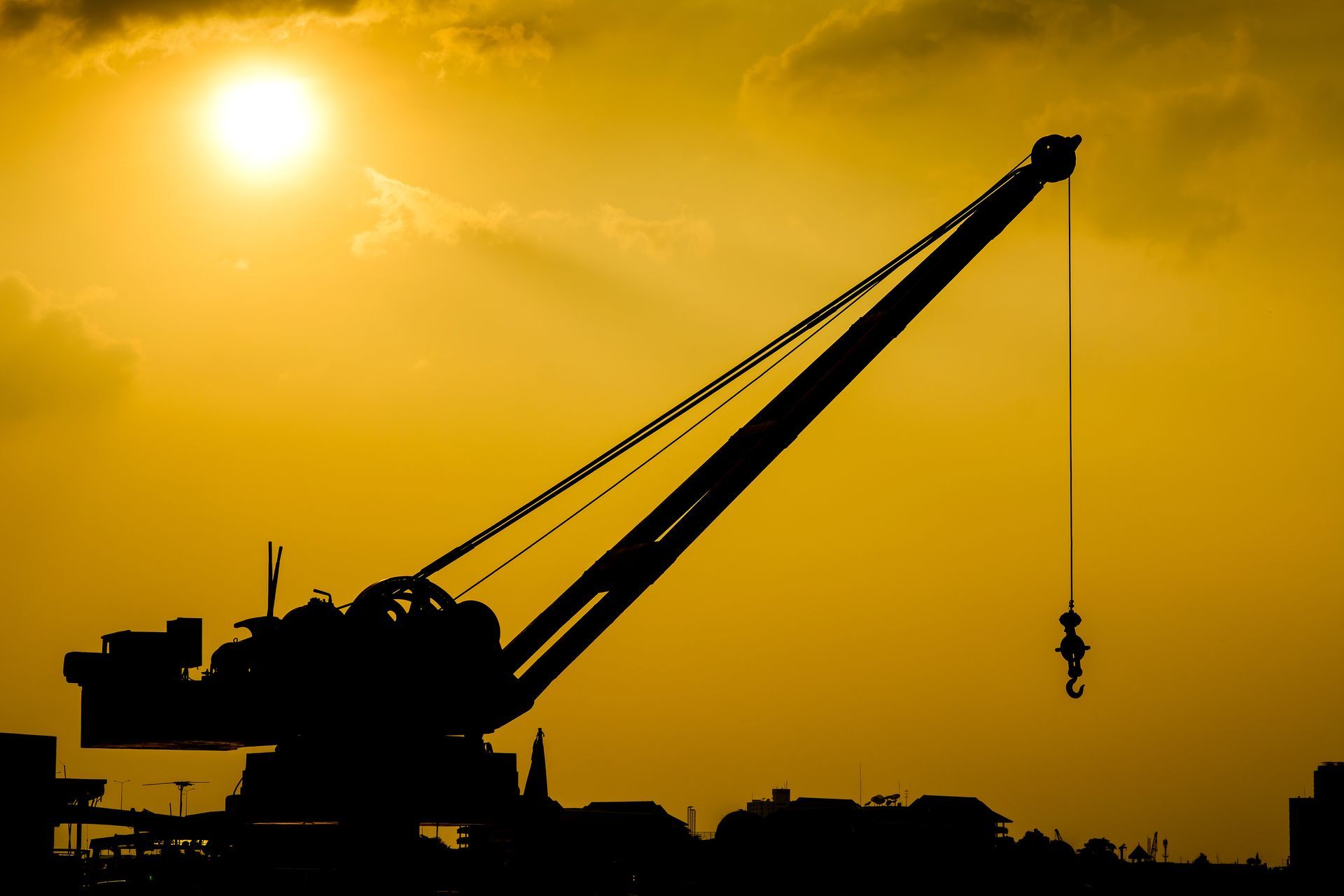 A large crane is silhouetted against a sunset sky