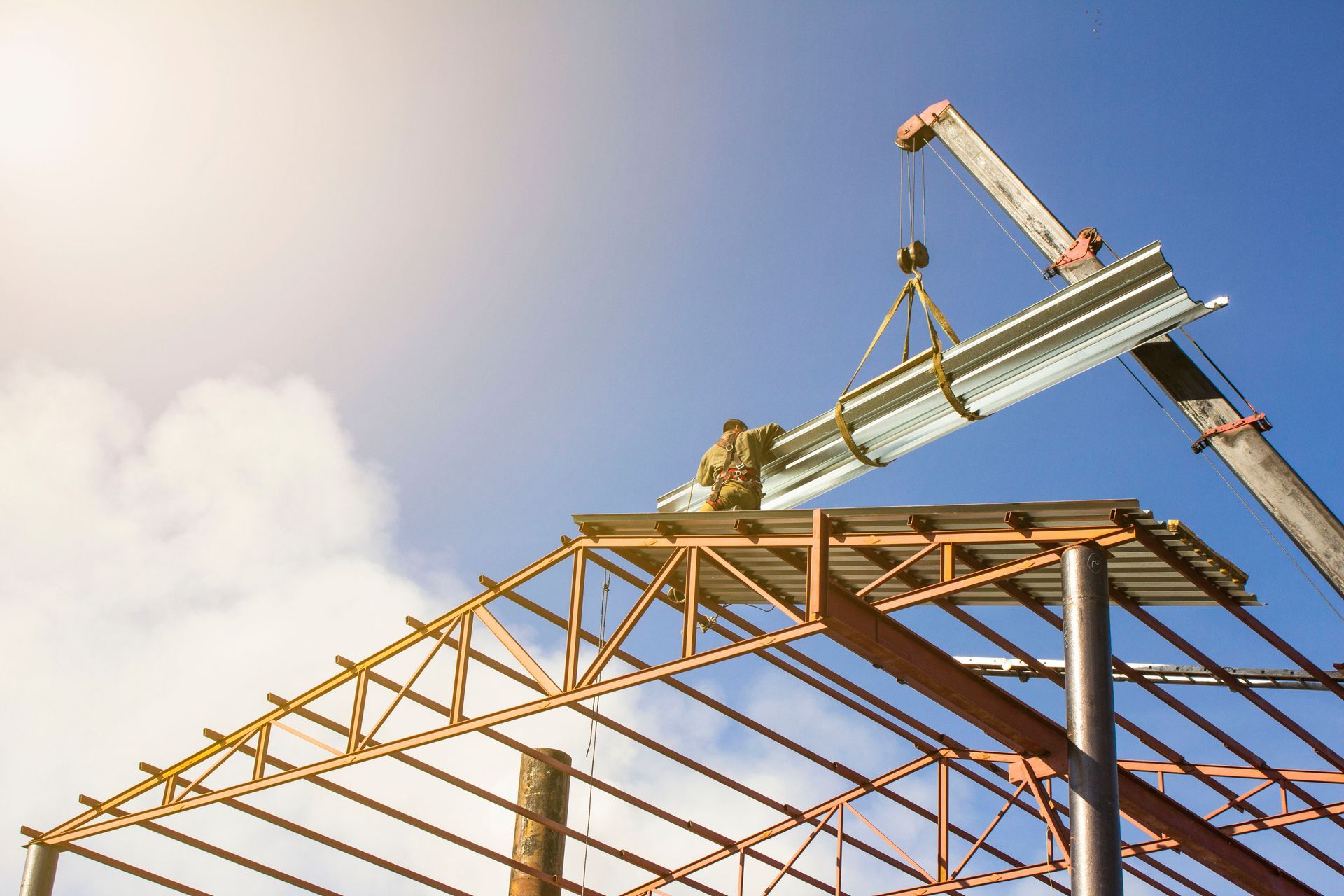 A man is standing on top of a metal structure being lifted by a crane.