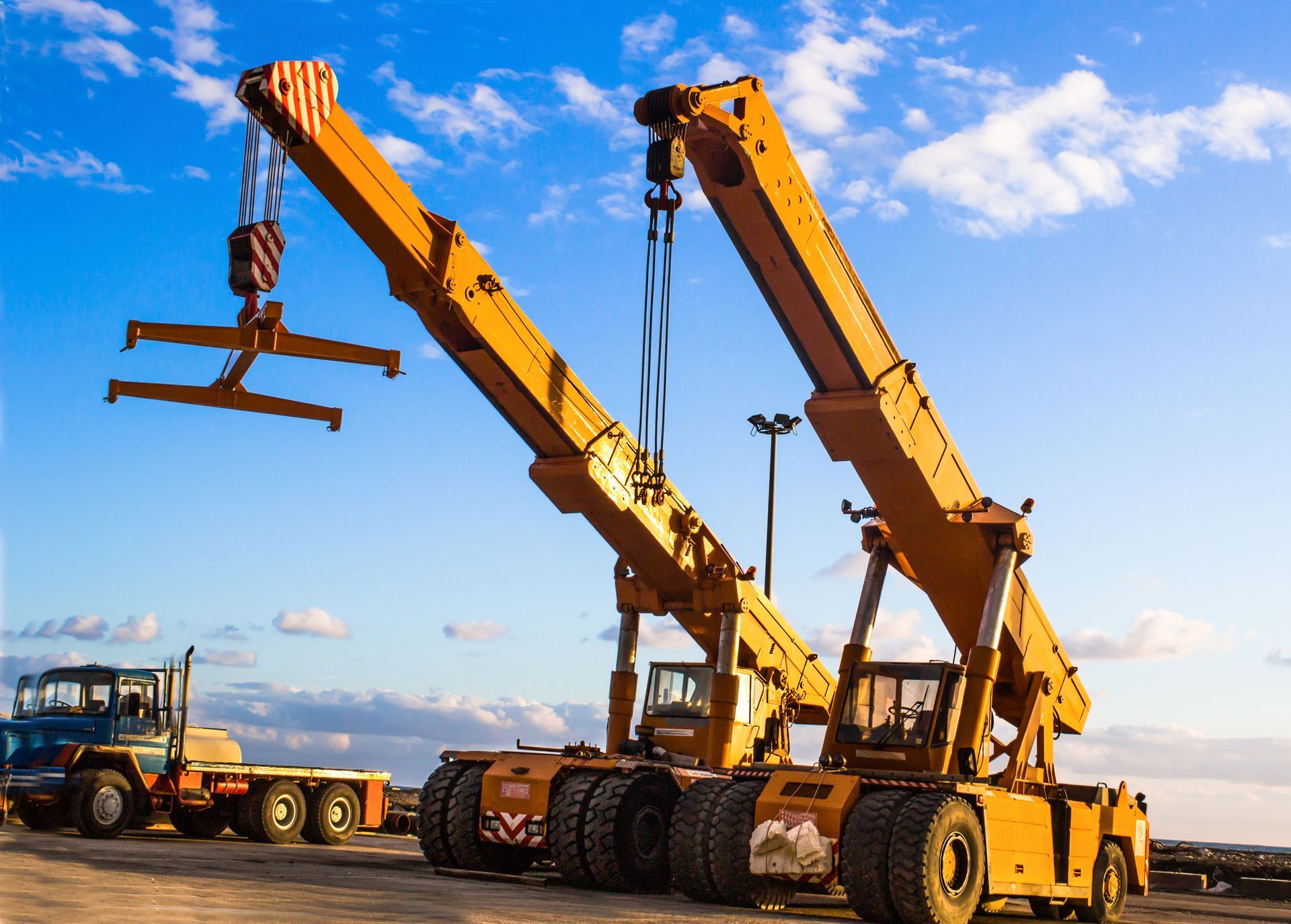 Two yellow cranes are sitting next to each other in a parking lot.