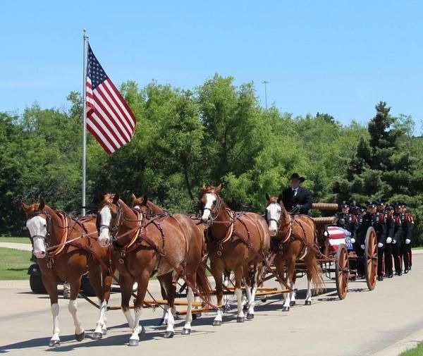 American flag waving on a flagpole against a partly cloudy blue sky.