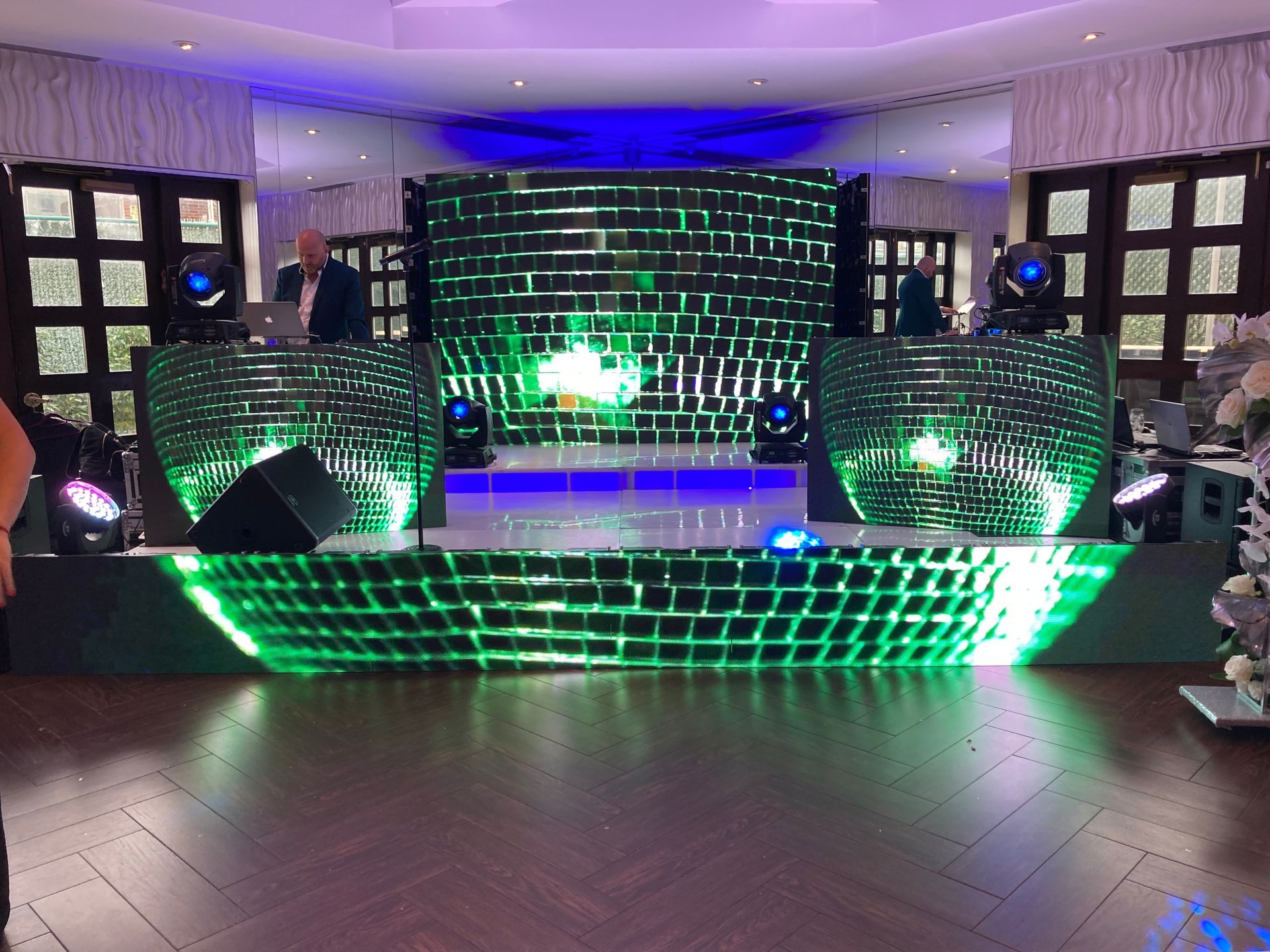 LED Video Wall and A dj is standing in front of a stage with green lights.