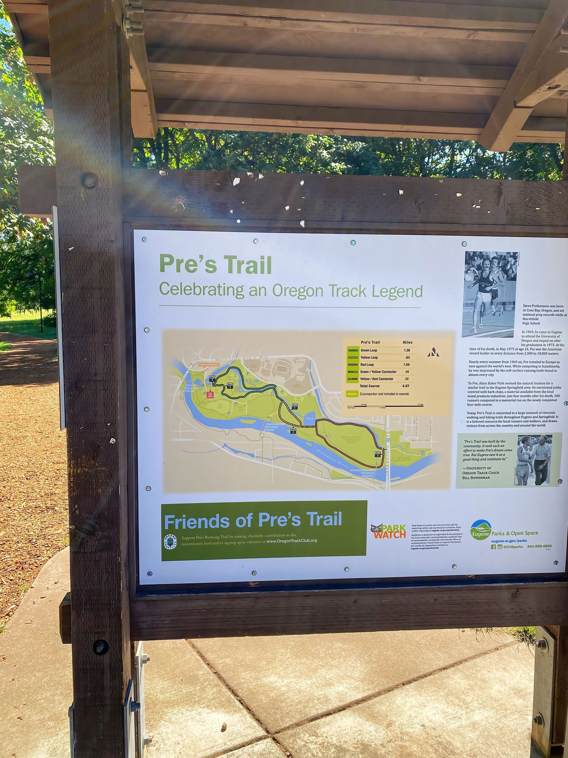 A wooden information board at the entrance of Pre’s Trail in Eugene, Oregon, displaying a map and historical details about the trail. The board has the title 