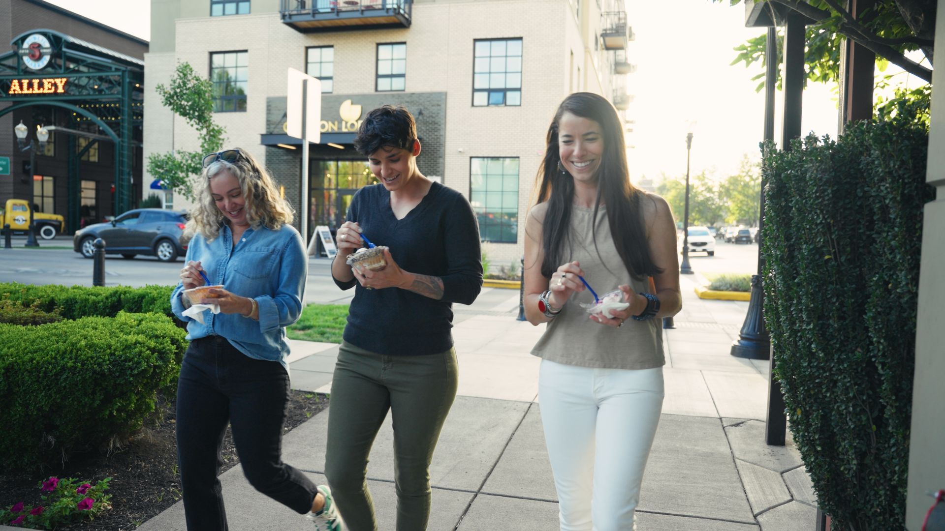 Three friends stroll through the 5th Street Public Market neighborhood in Eugene, enjoying locally m