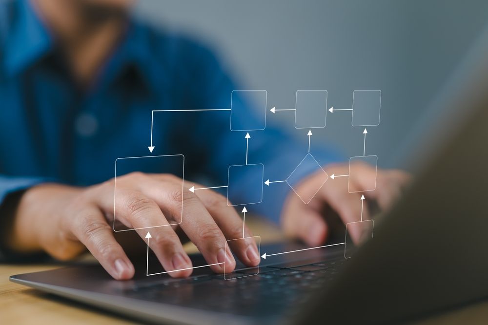 A man is typing on a laptop computer with a diagram on the screen.