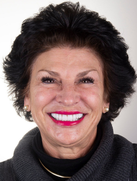 A person with dark, short hair wearing a dark grey turtleneck sweater