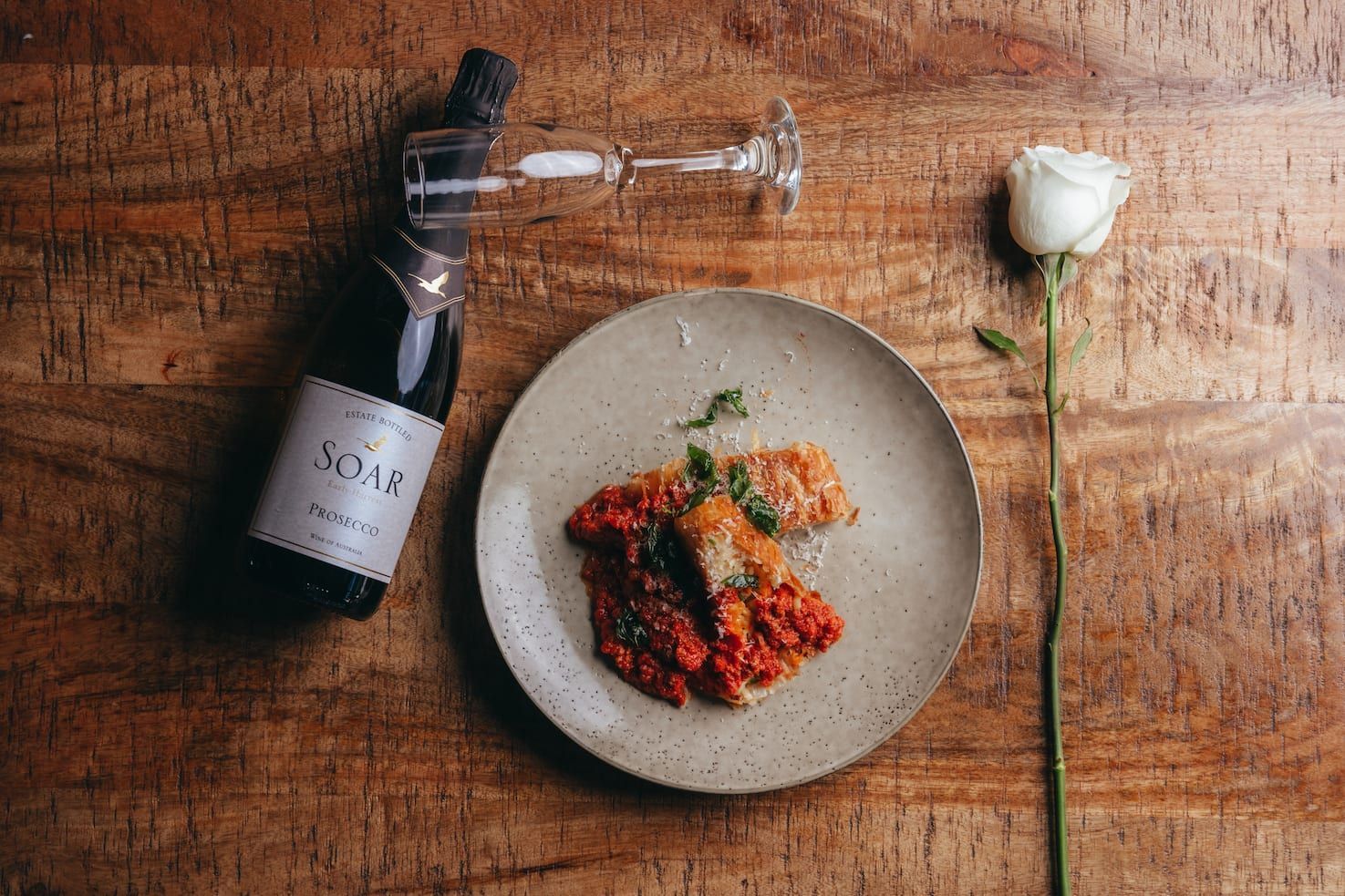 A plate of food and a bottle of wine on a wooden table.