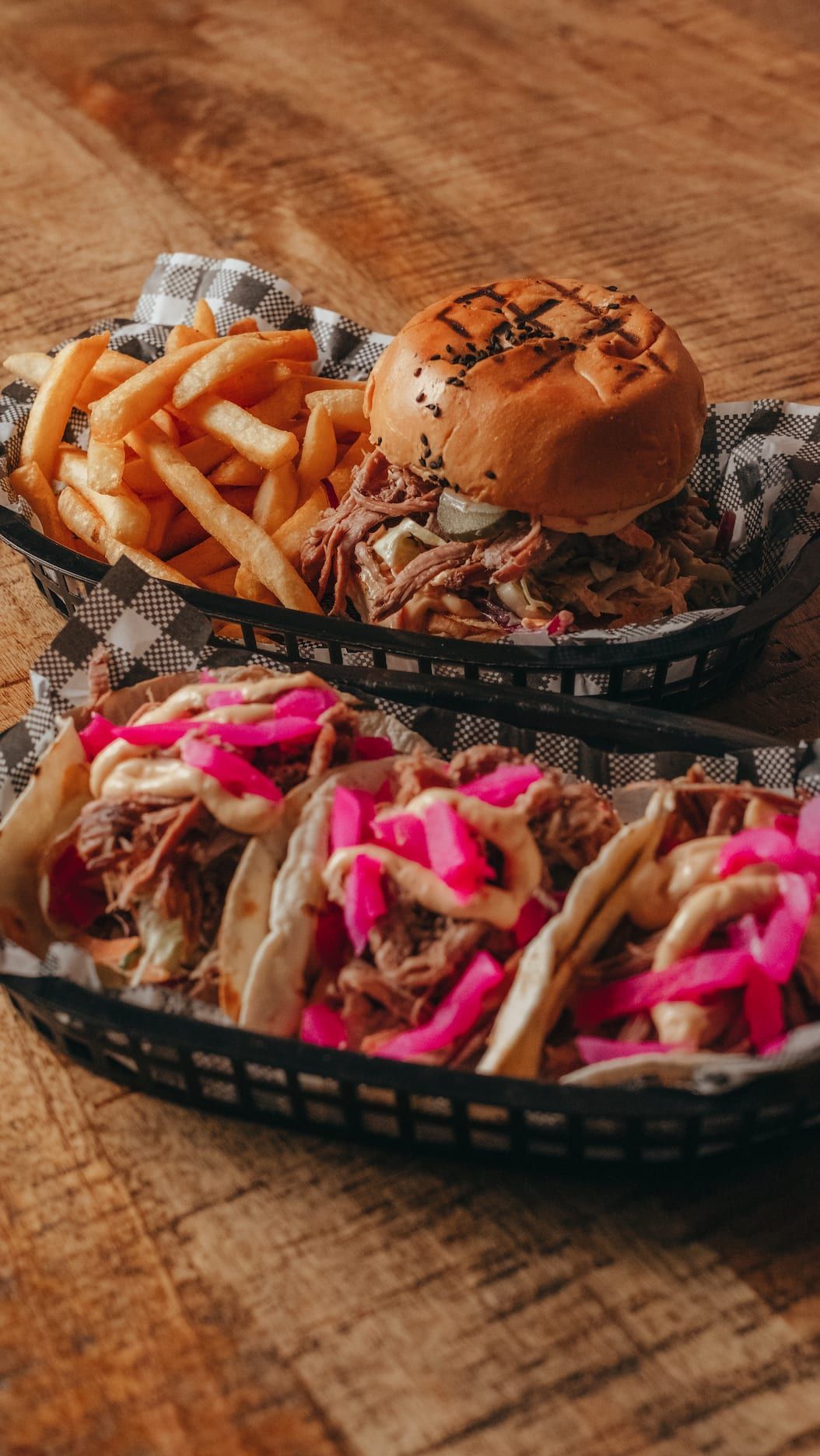 Two baskets of food are sitting on a wooden table.