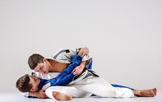 Two young boys performing brazilian Jiu Jitsu on ground and submission holds.