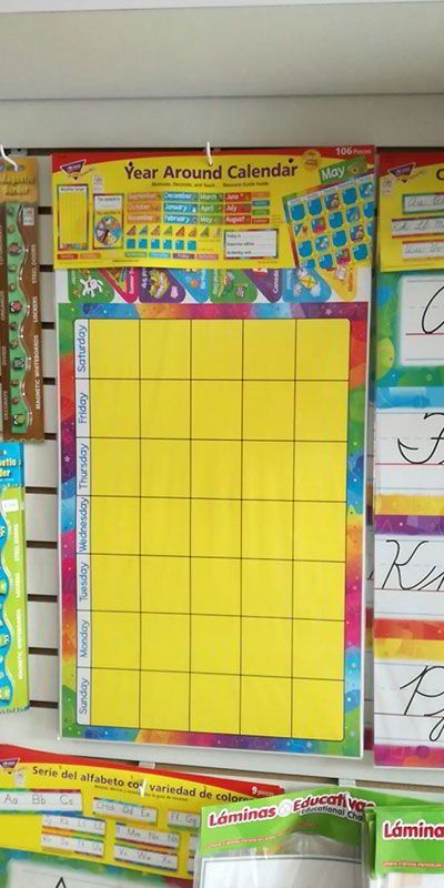 Un calendario amarillo está colgado en una pared junto a otros calendarios.