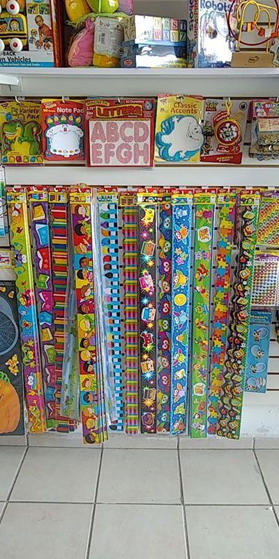 Un estante lleno de muchos juguetes y papel de regalo en una tienda.