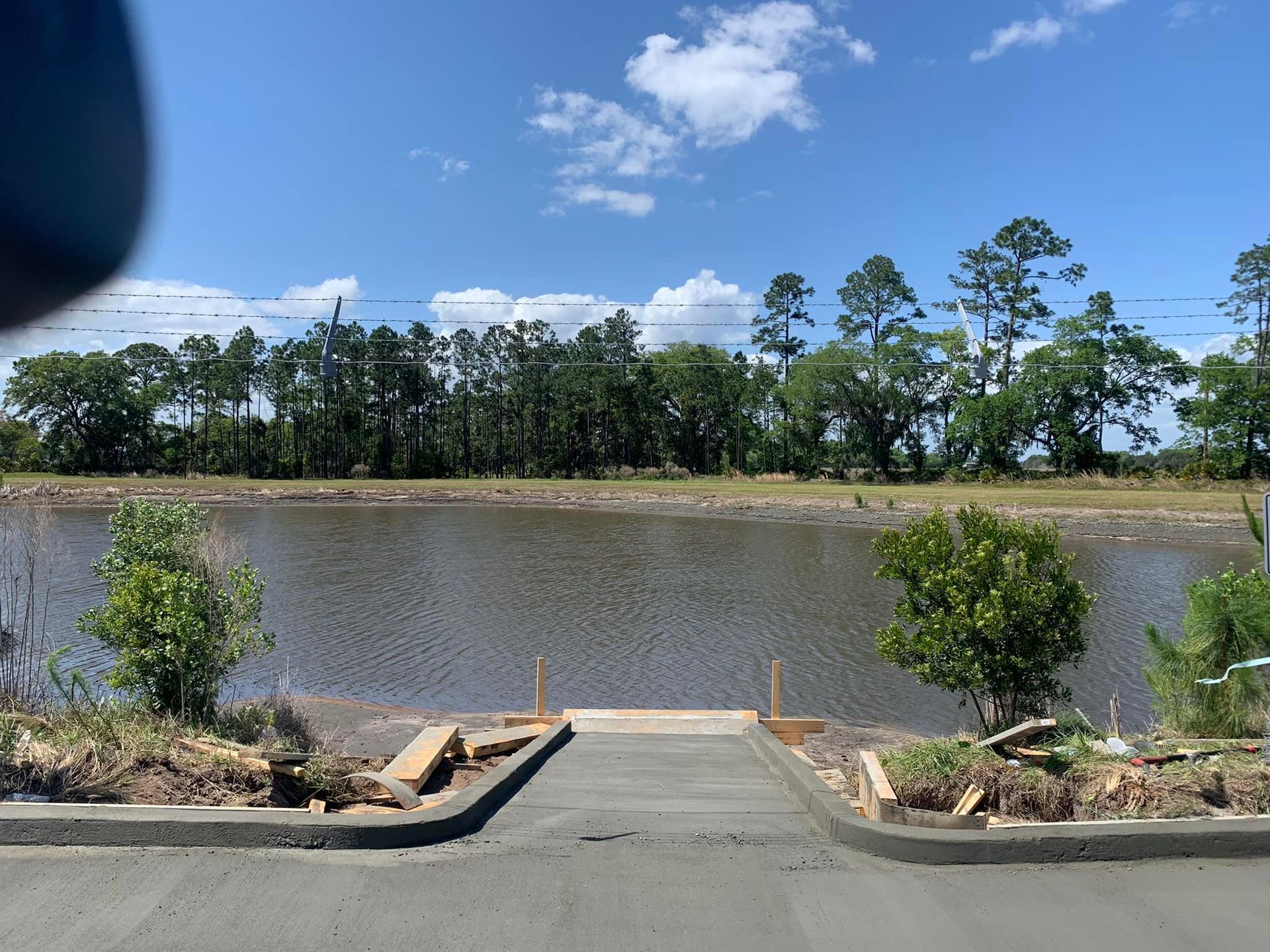 A concrete walkway leading to a lake with trees in the background.