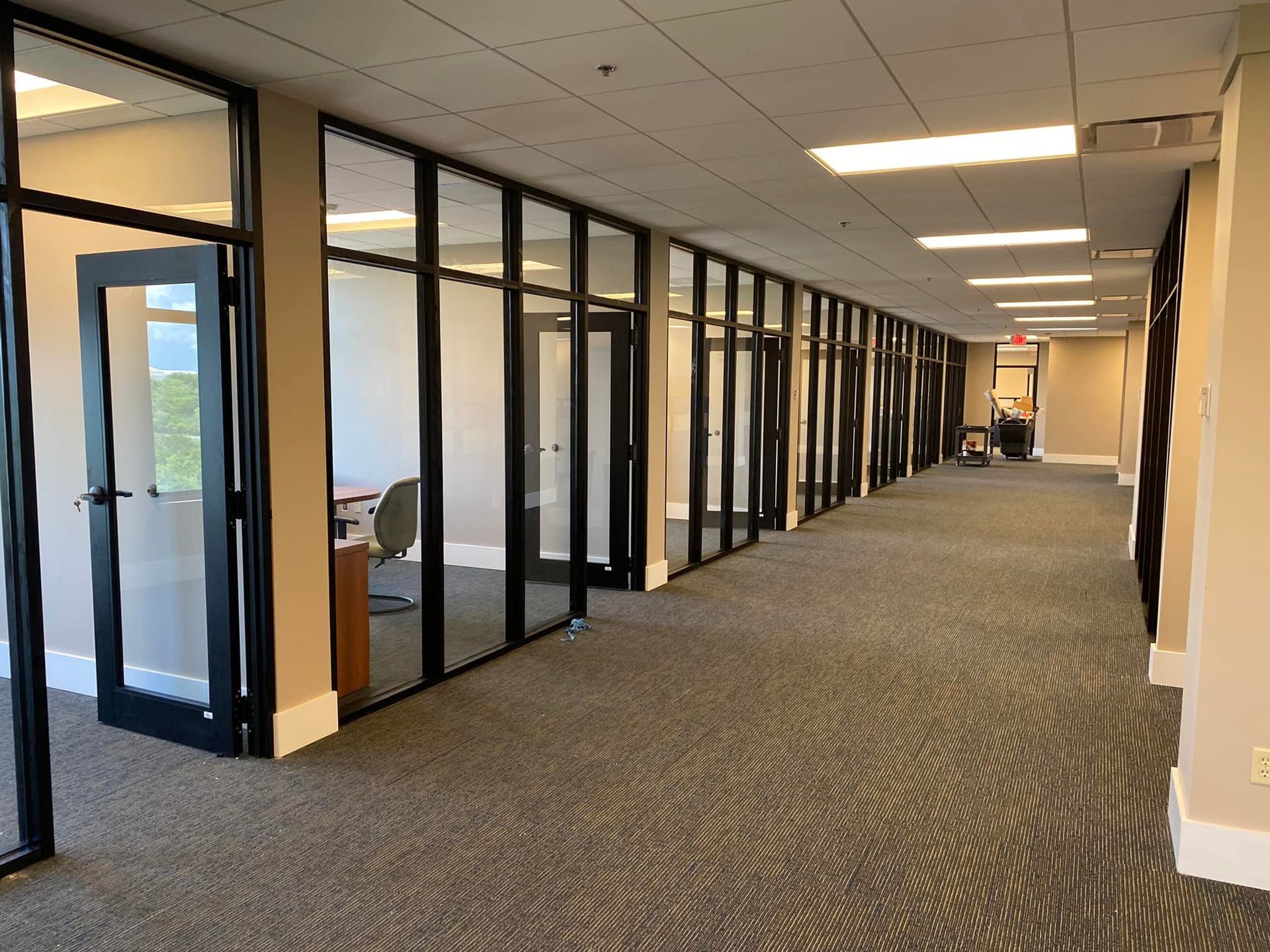 A long hallway with a lot of windows and doors in an office building.