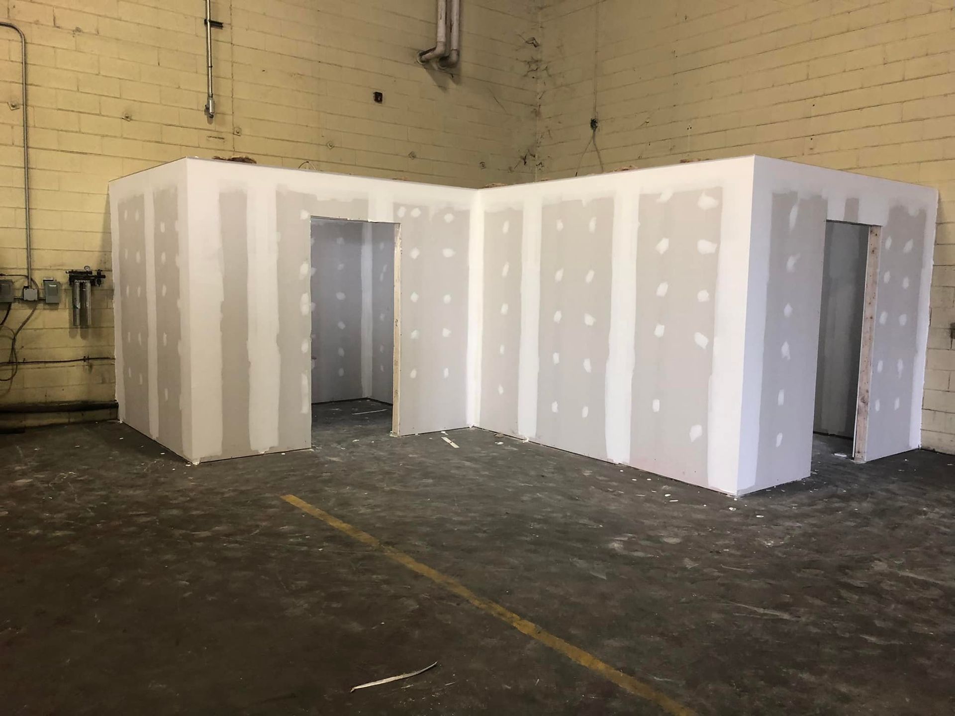 A room with drywall walls and doors in a warehouse.