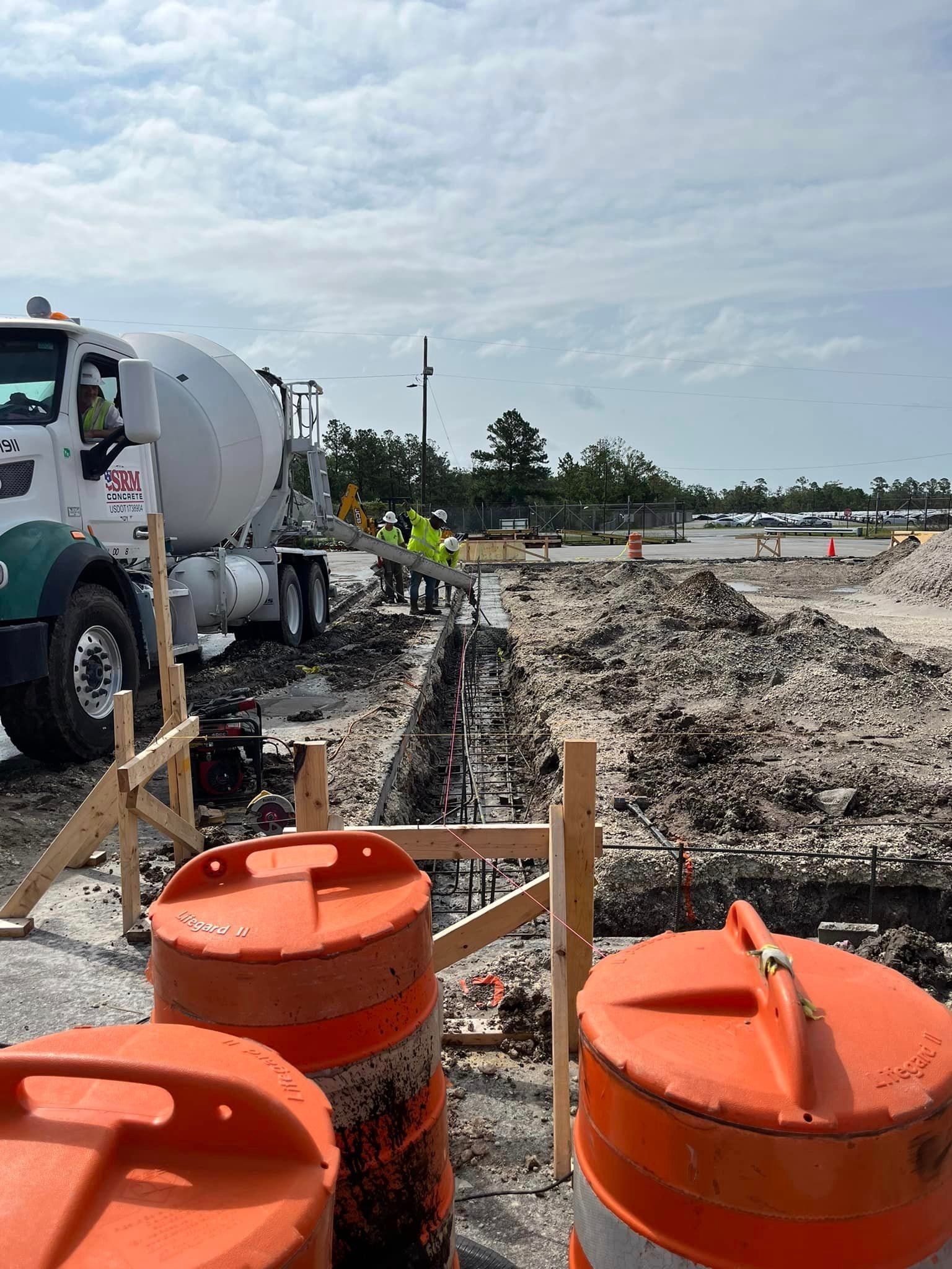 A construction site with a concrete mixer truck and orange cones.