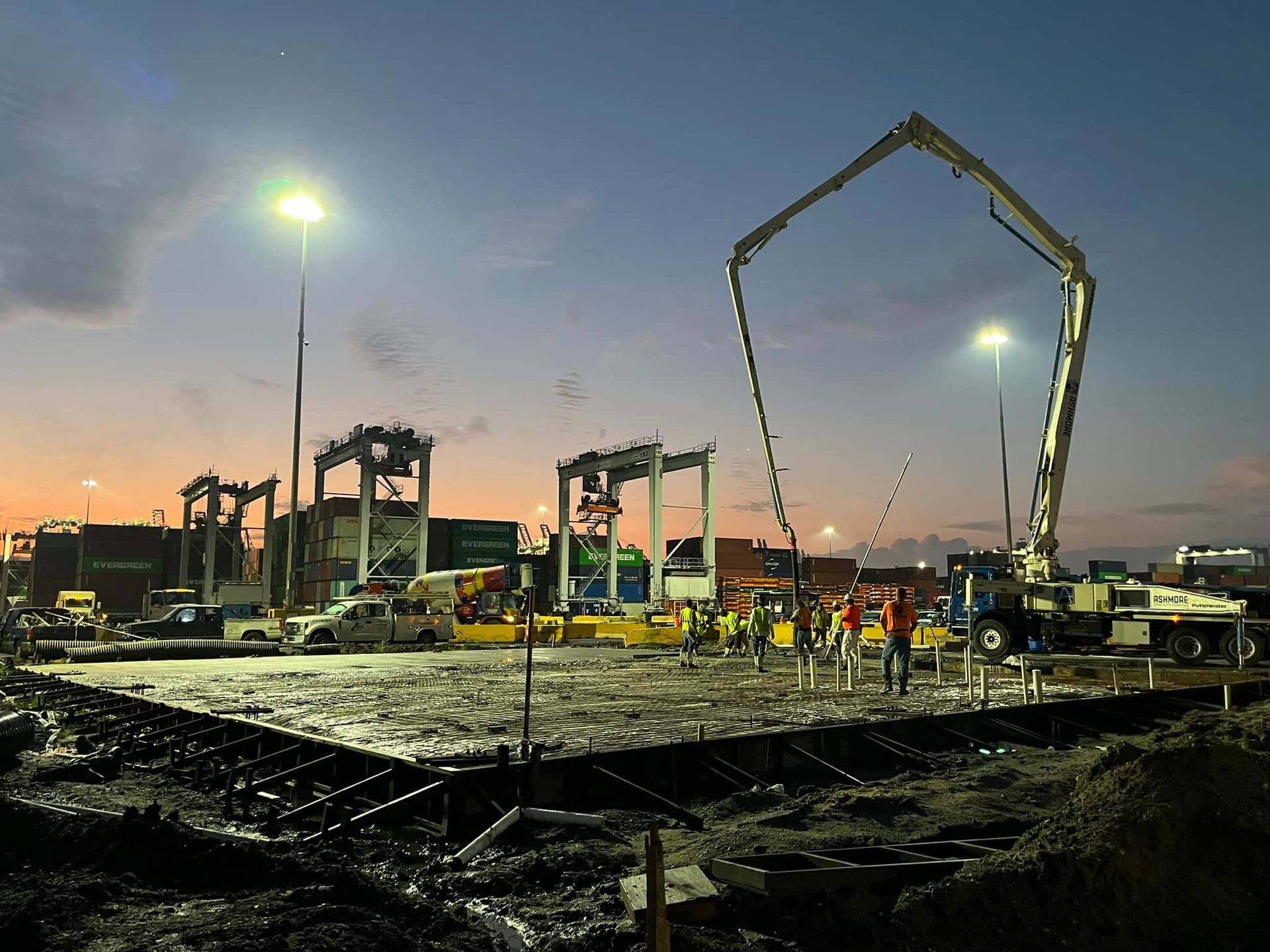 A construction site at night with a concrete pump in the foreground