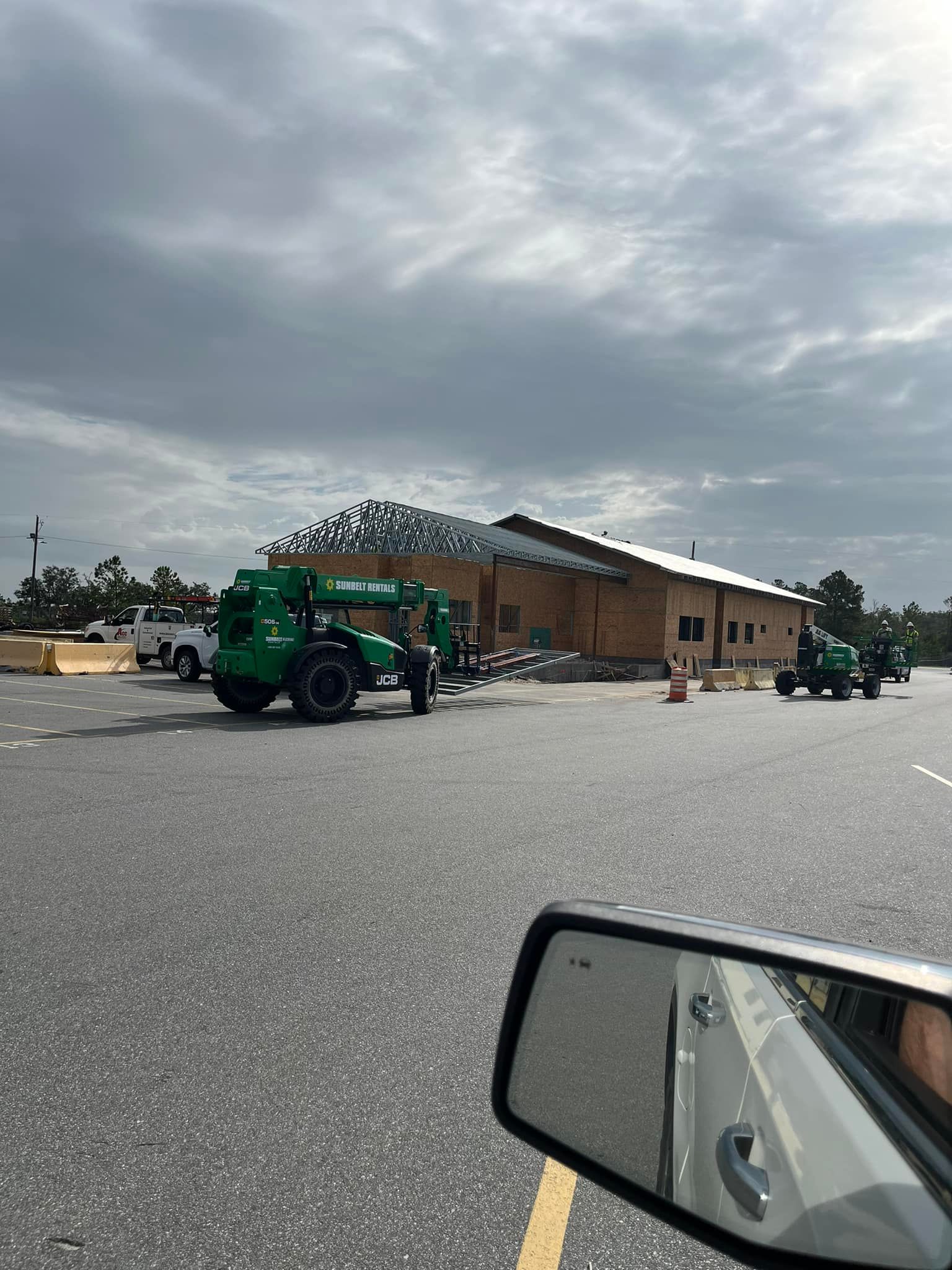 A tractor is parked in a parking lot in front of a building under construction.