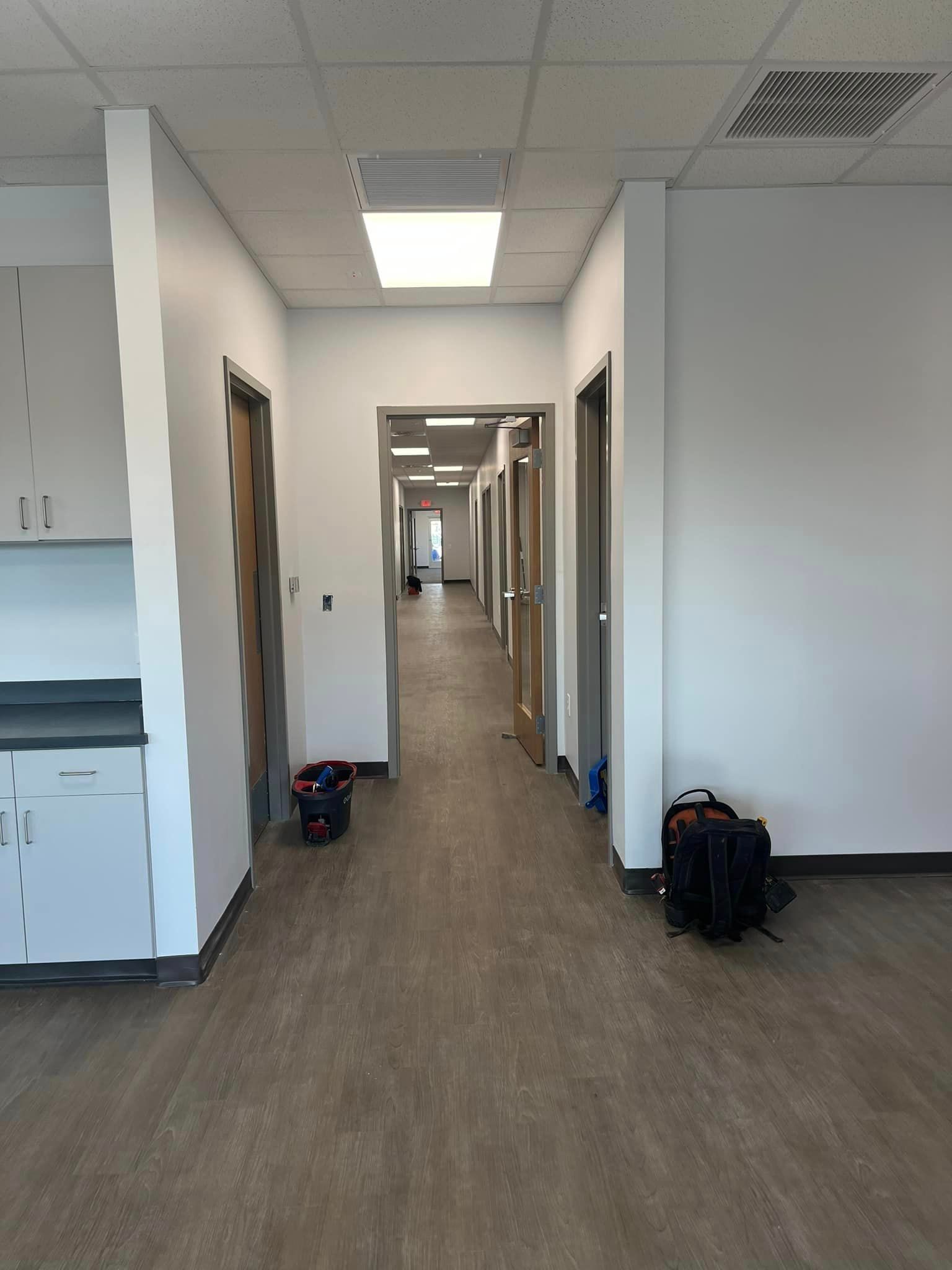 A long hallway in a building with a backpack on the floor.