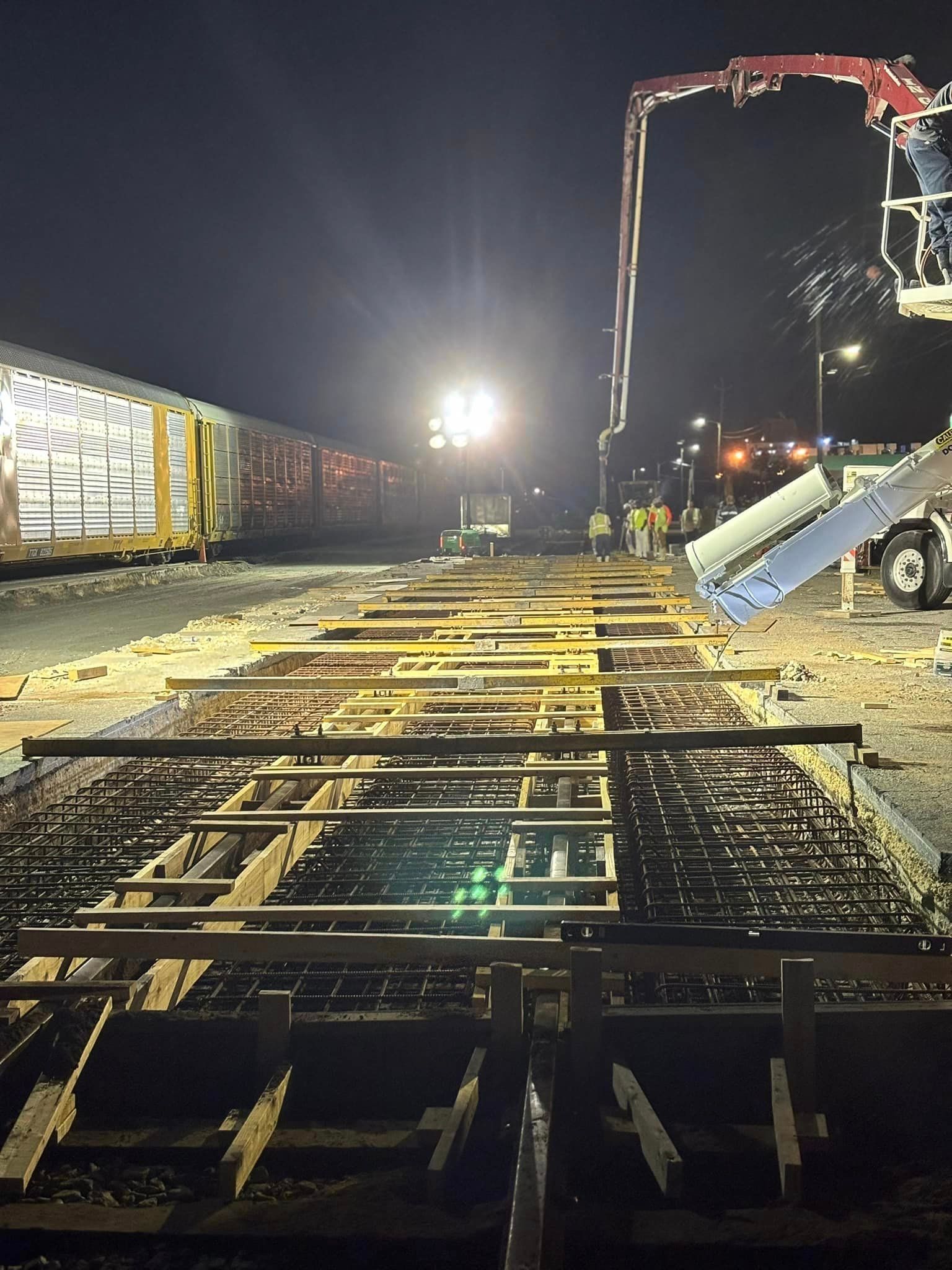 A construction site at night with a train in the background.
