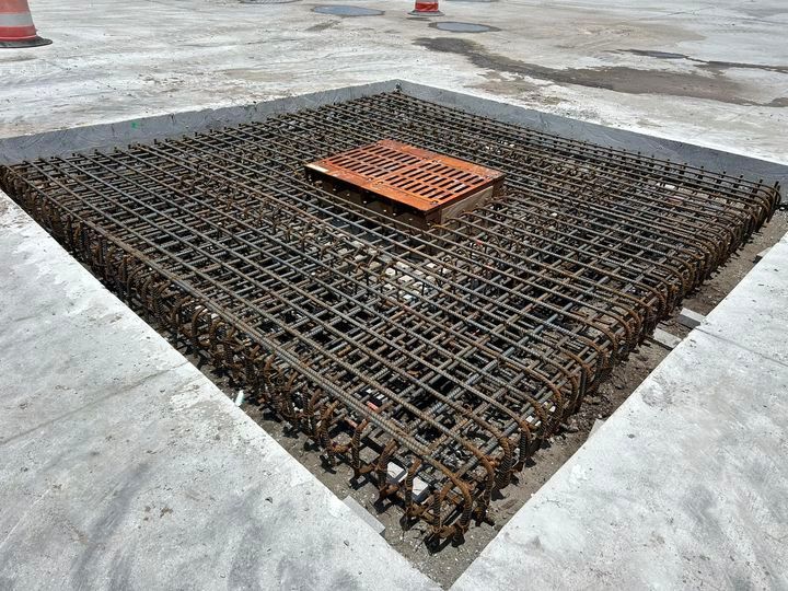 A metal grate is sitting on top of a concrete surface