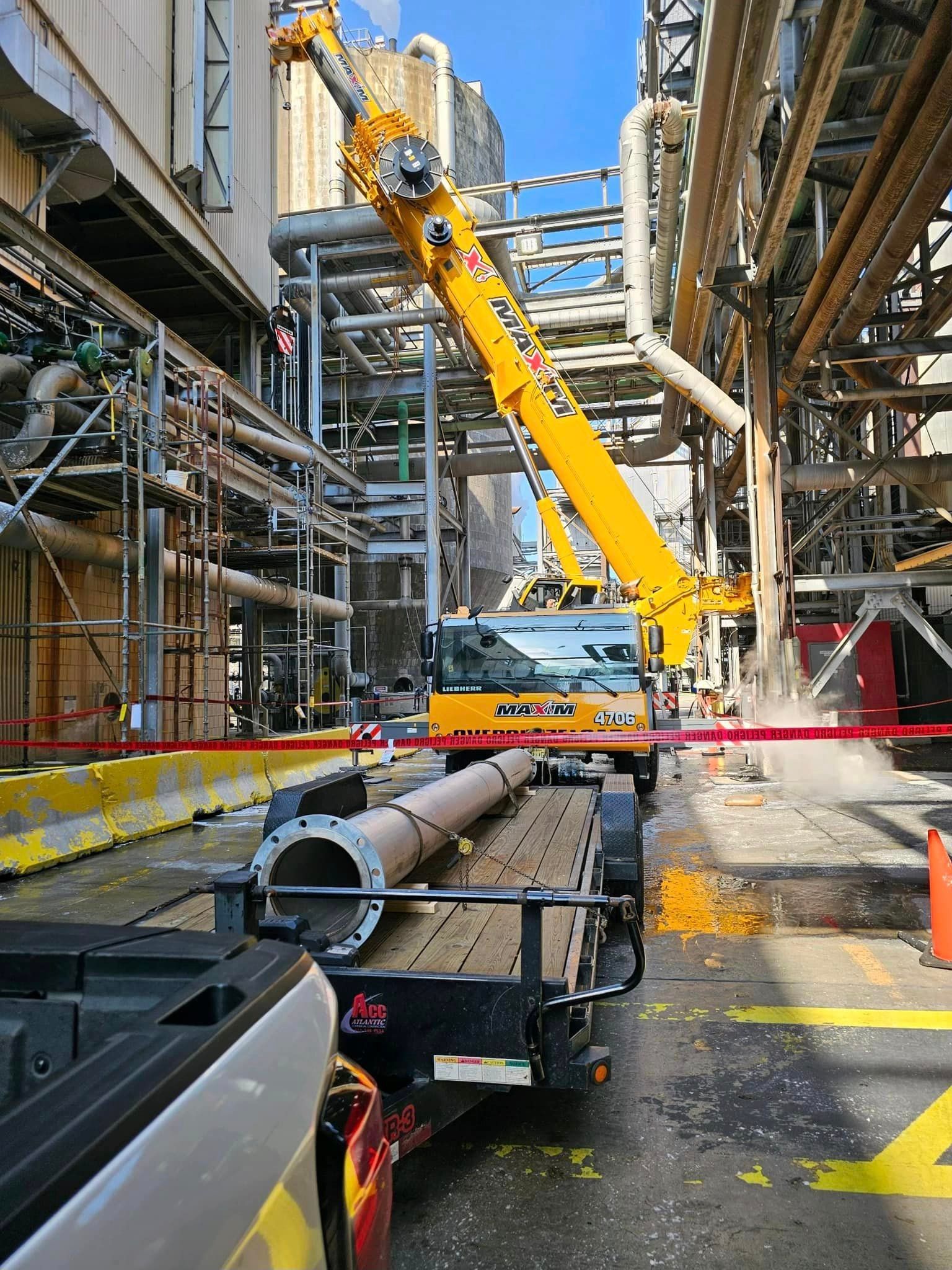 A large yellow crane is sitting on top of a trailer in a factory.